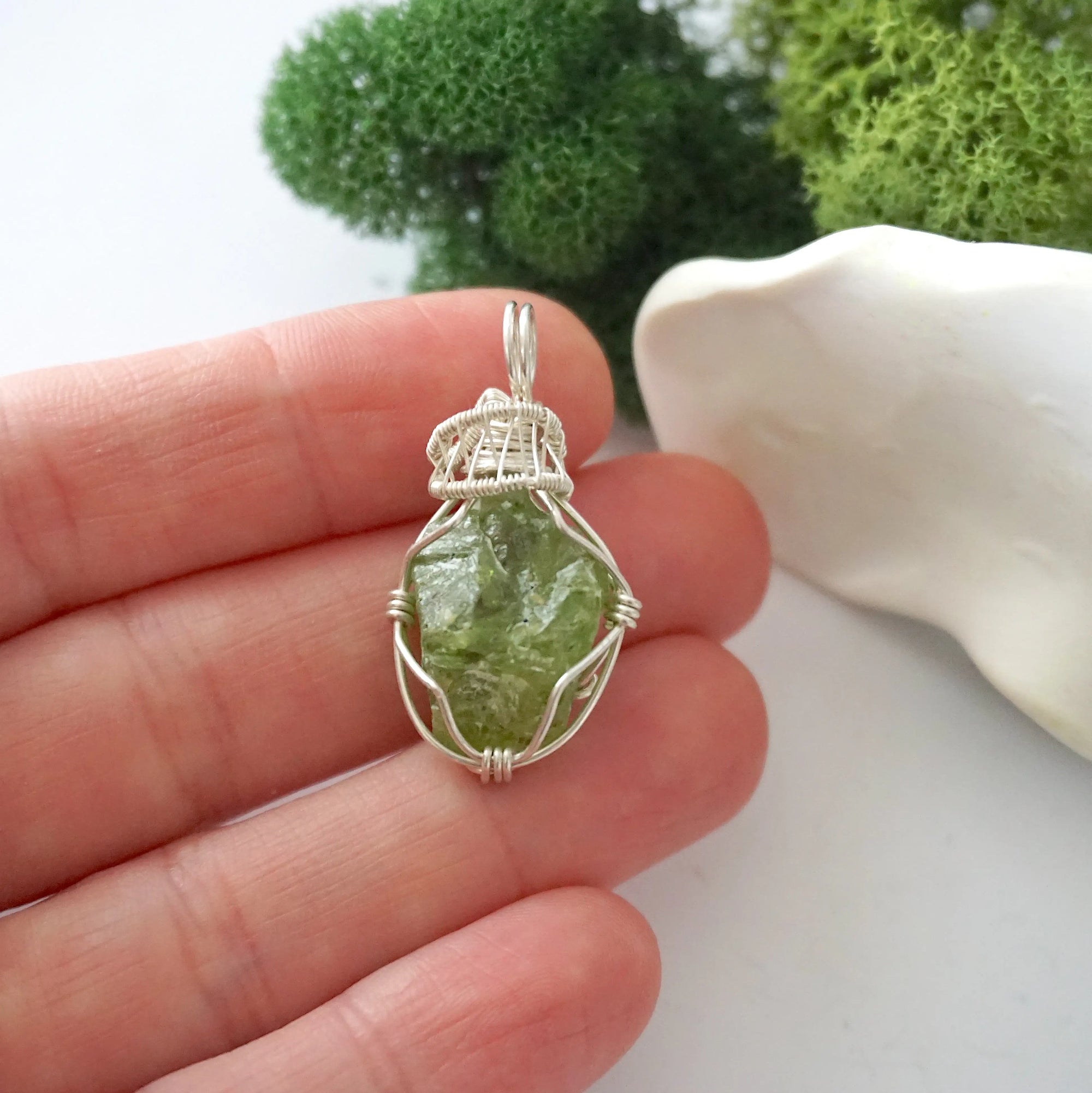 Handmade raw peridot pendant held in hand showing size — natural green peridot stone wire wrapped in 925 sterling silver, approx. 1 inch, one of a kind