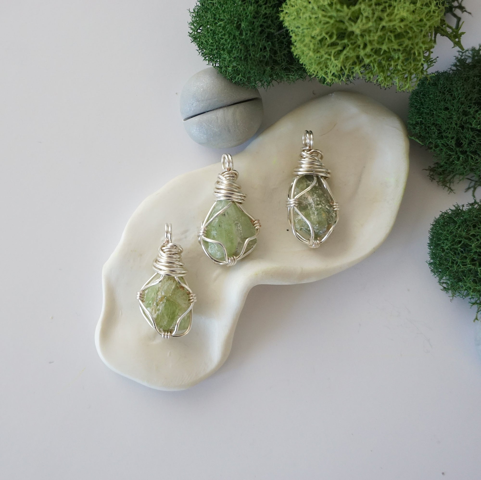 Three different raw peridot pendants displayed for variation reference