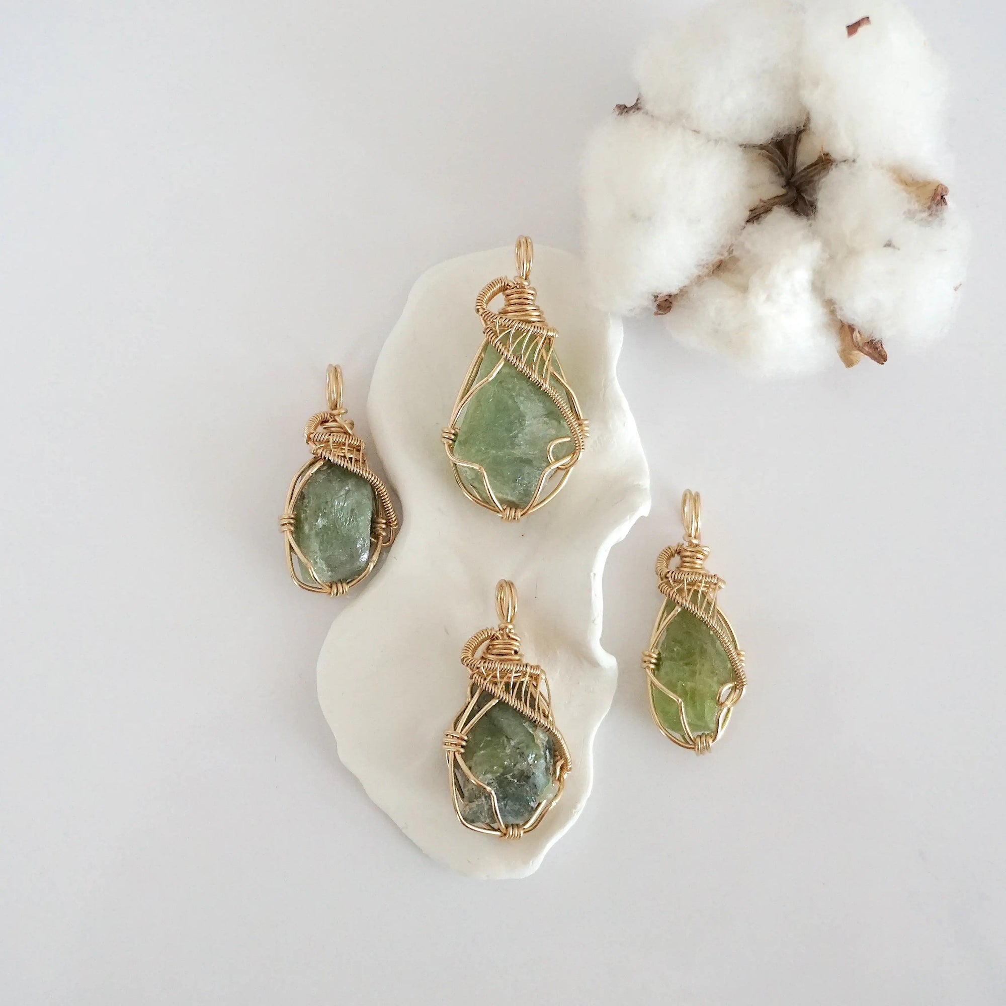 Four raw peridot pendants in 14k gold filled, showing natural variation in size, shape, and color. Handcrafted August birthstone jewelry by Designs by Nature Gems.