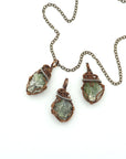 Three raw peridot pendants for men showing natural variation in size, shape, and olive green colour — handcrafted two-tone wire wrapped August birthstone necklaces