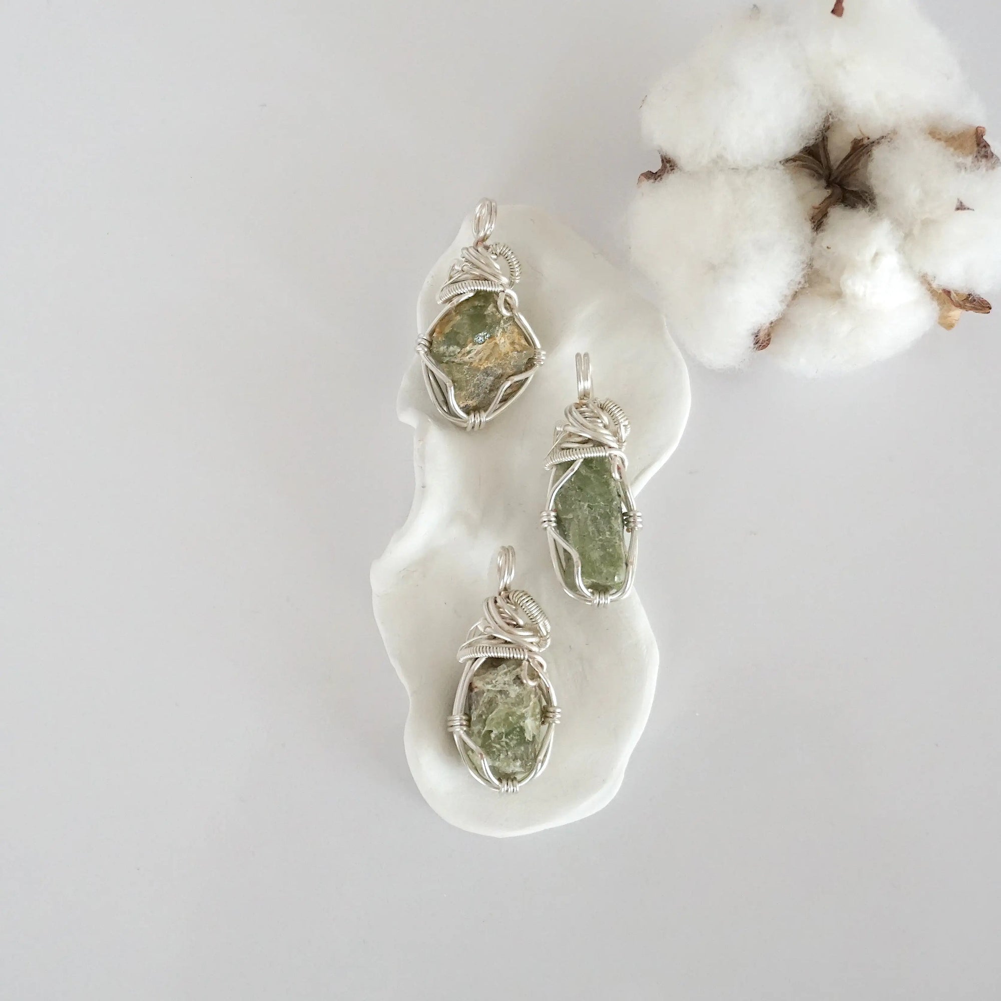 Three raw peridot pendants showing natural variation in stone size, shape, and green colour — each one of a kind, August birthstone, silver wire wrapped, Designs by Nature Gems