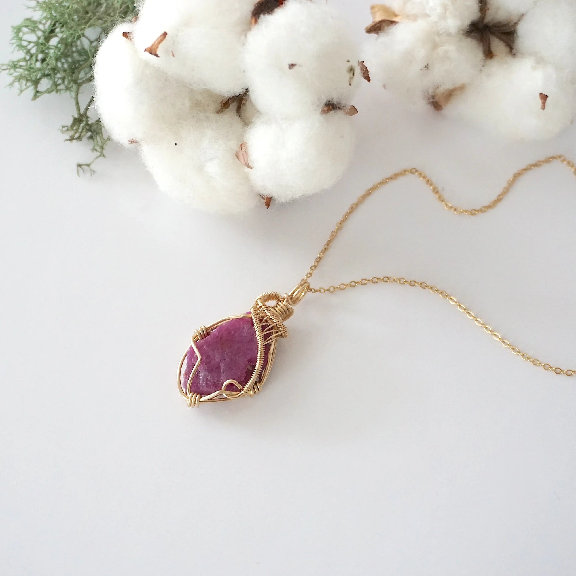 Raw pink ruby necklace in 14k gold filled laying flat. Handcrafted July birthstone jewelry for women by Designs by Nature Gems.