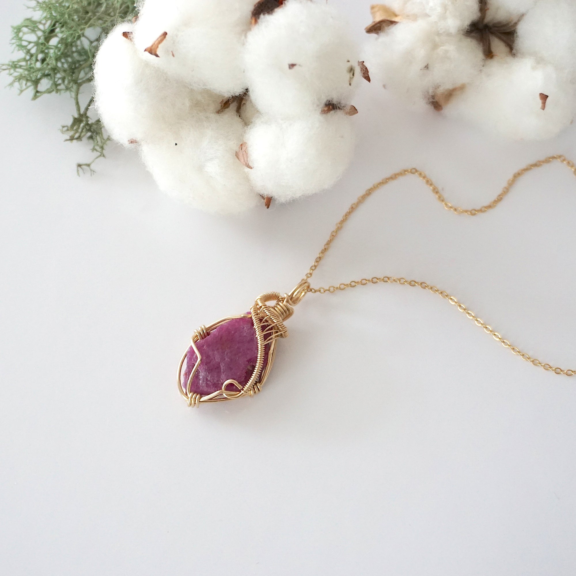 Raw pink ruby necklace in 14k gold filled laying flat. Handcrafted July birthstone jewelry for women by Designs by Nature Gems.