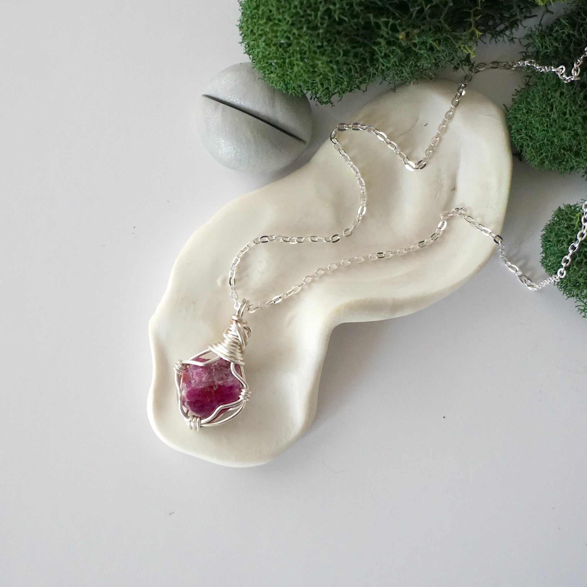 Simple raw pink ruby necklace with silver plated brass chain laying flat