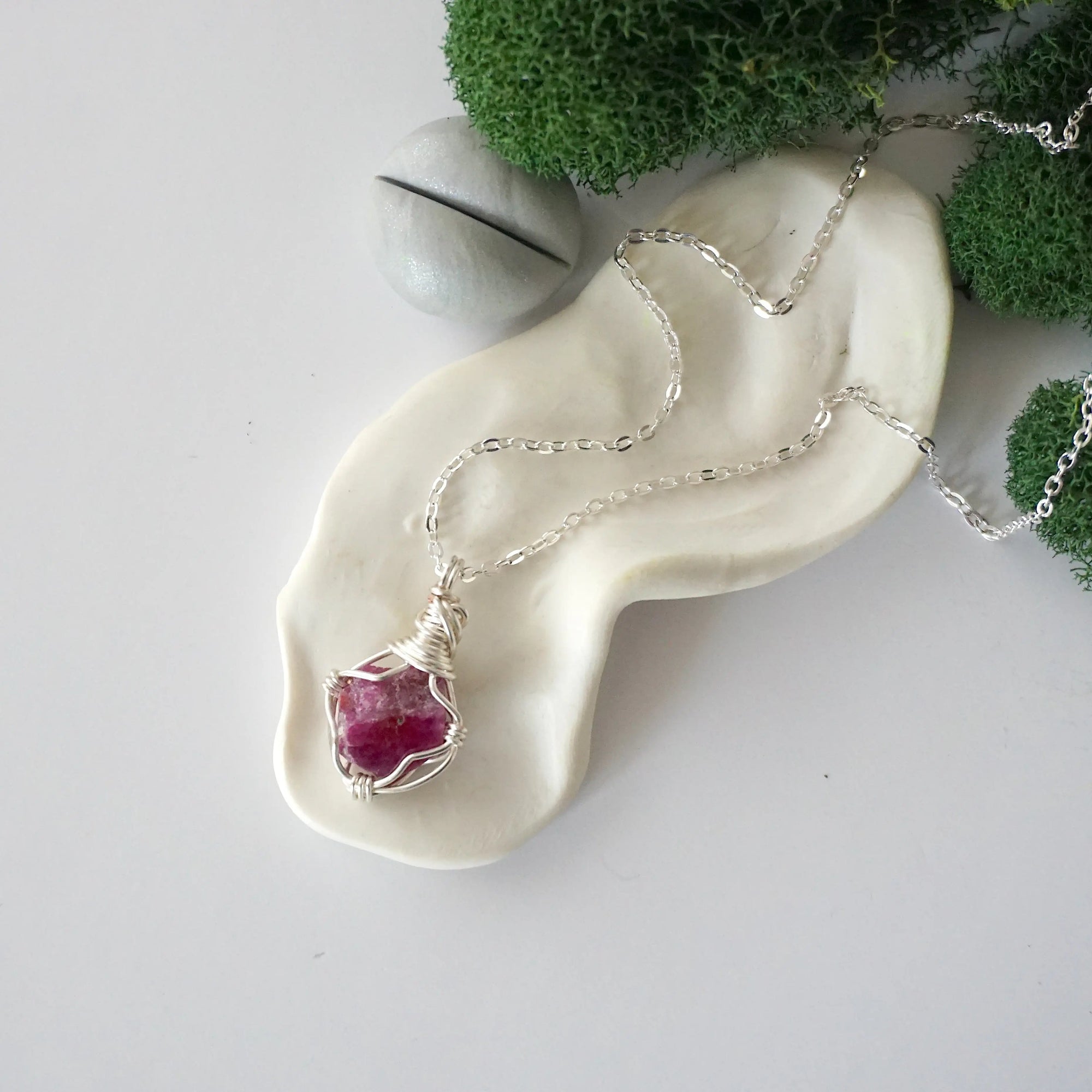 Simple raw pink ruby necklace with silver plated brass chain laying flat