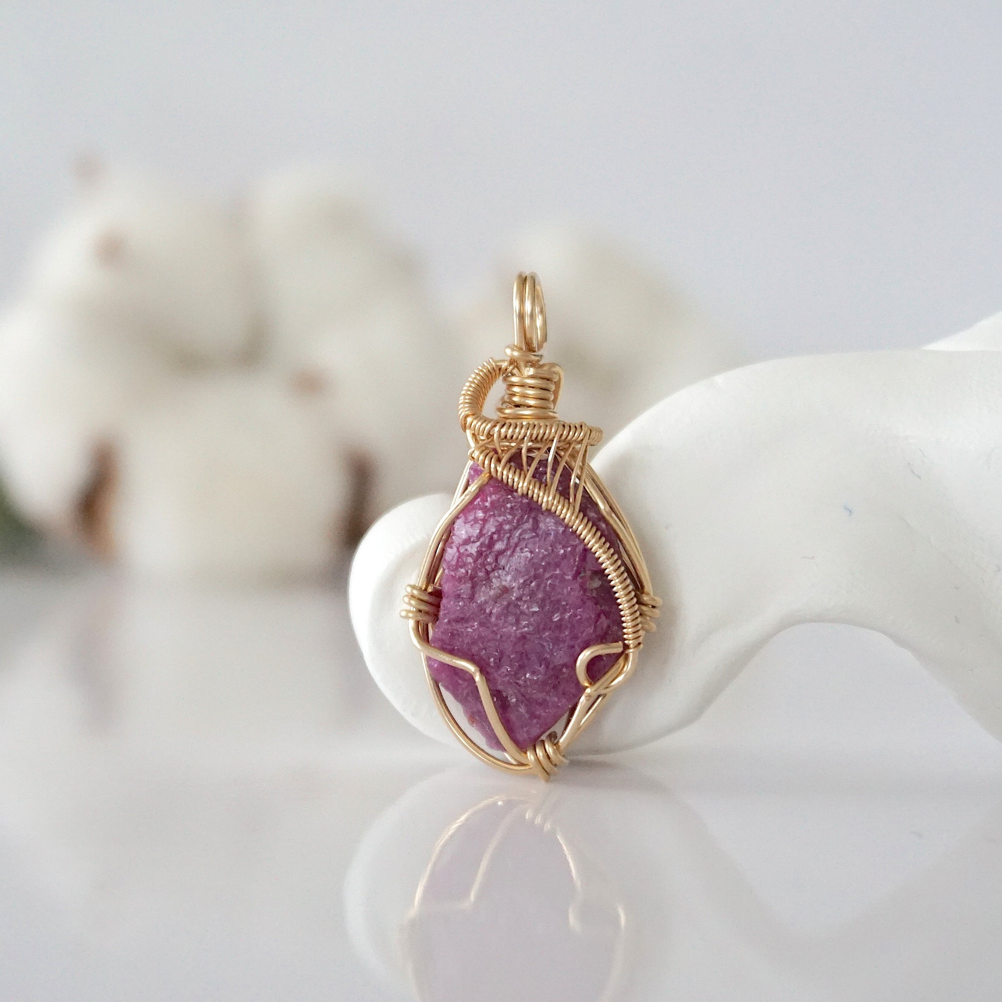 Detailed front view of raw pink ruby pendant in 14k gold filled. Unique wire wrapped July birthstone jewelry by Designs by Nature Gems.