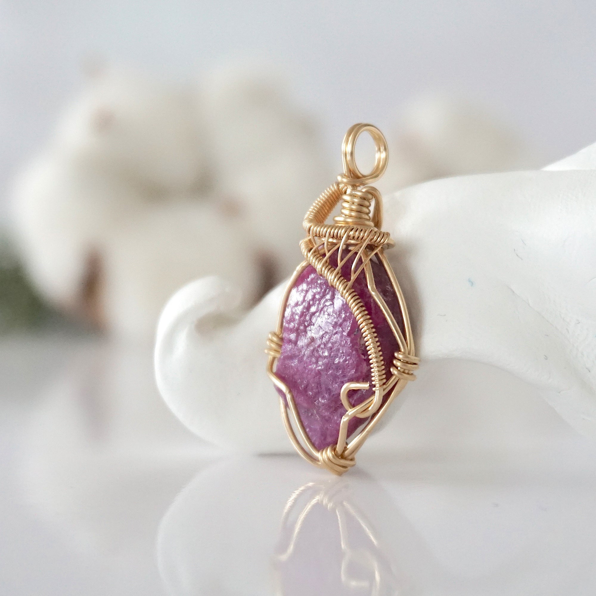 Side view of raw pink ruby pendant in 14k gold filled, showing artisan wire wrapping. Handcrafted July birthstone necklace by Designs by Nature Gems.