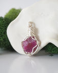 Detailed side angle view of simple raw pink ruby pendant in silver wire