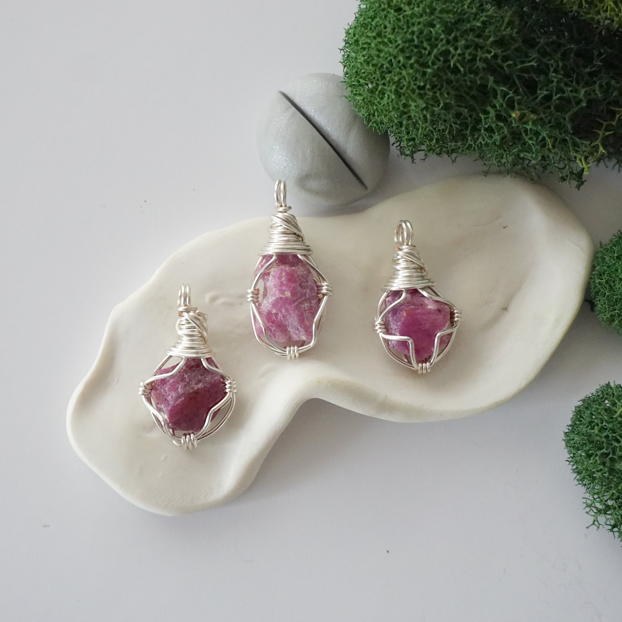 Three different raw pink ruby pendants displayed for variation reference