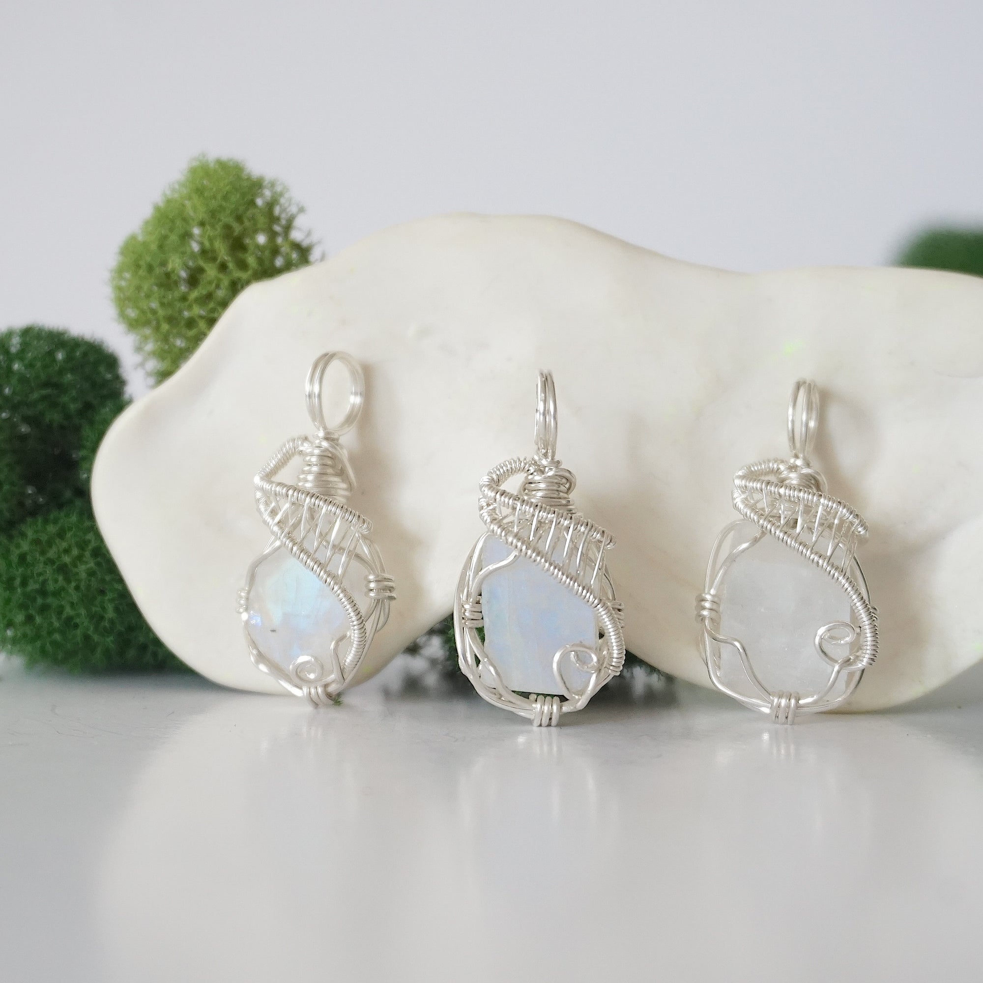 Three raw rainbow moonstone necklaces showing natural crystal variations and blue flash in handmade wire wrapped pendants