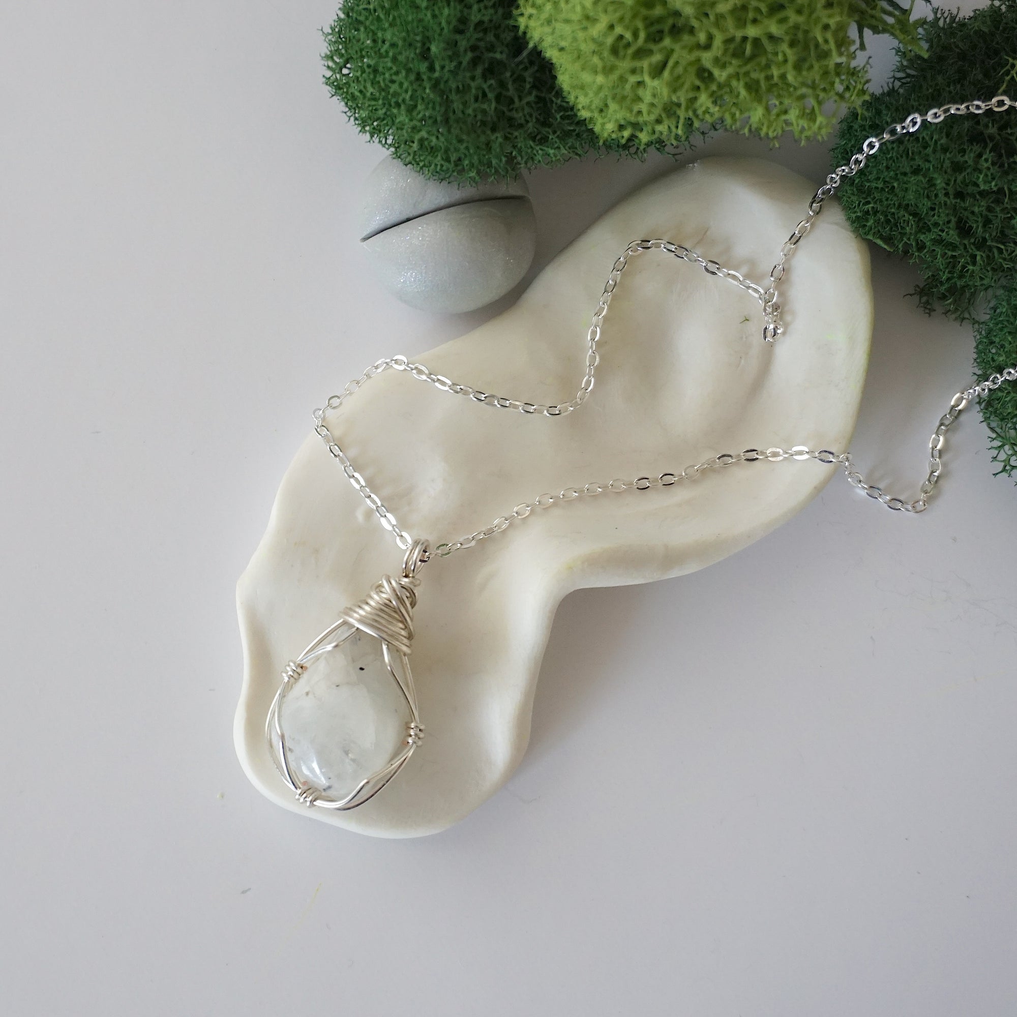 Simple raw rainbow moonstone necklace with silver plated brass chain laying flat