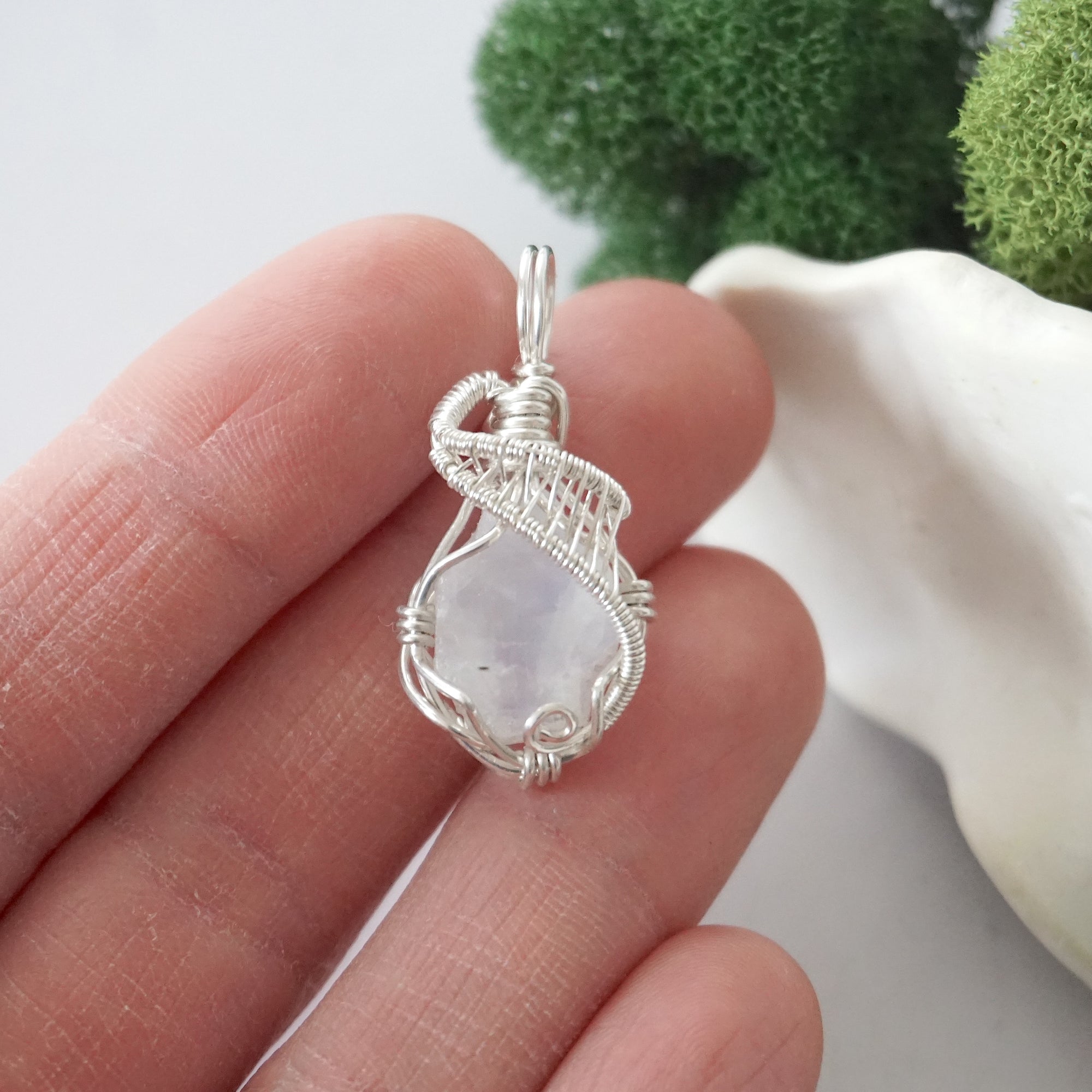 Raw rainbow moonstone crystal pendant wire wrapped in sterling silver held in hand showing size