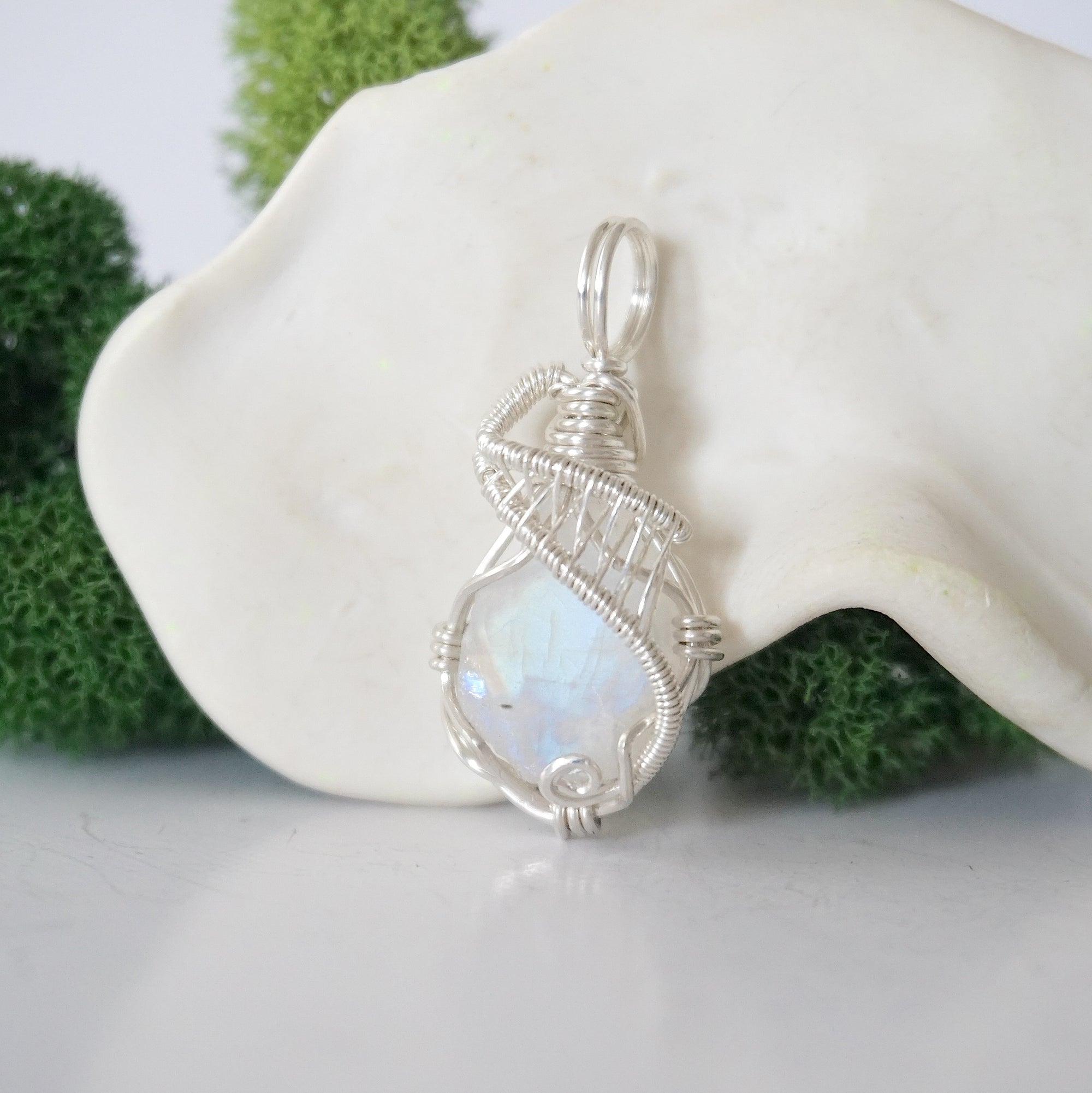 Close up front view of raw rainbow moonstone crystal with detailed 925 sterling silver wire wrapping