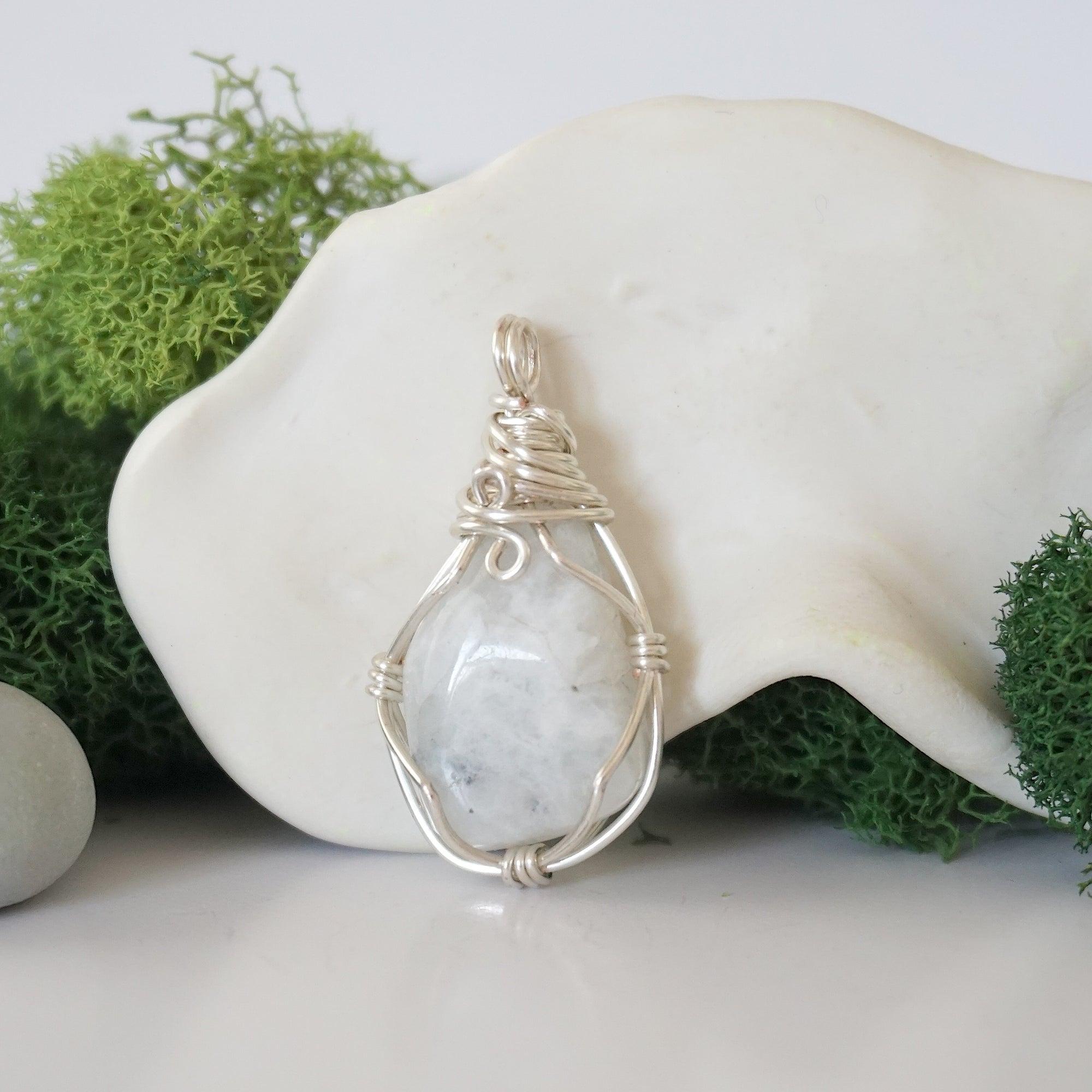 Back angle look at simple raw rainbow moonstone pendant with silver wire wrapping