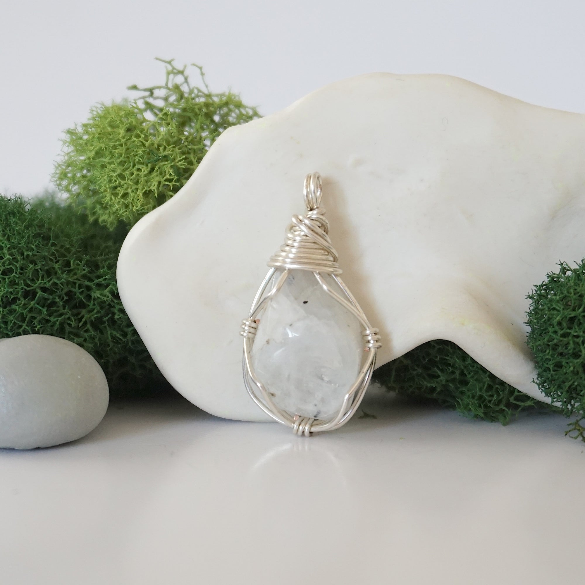 Detailed front angle view of simple raw rainbow moonstone pendant in silver wire