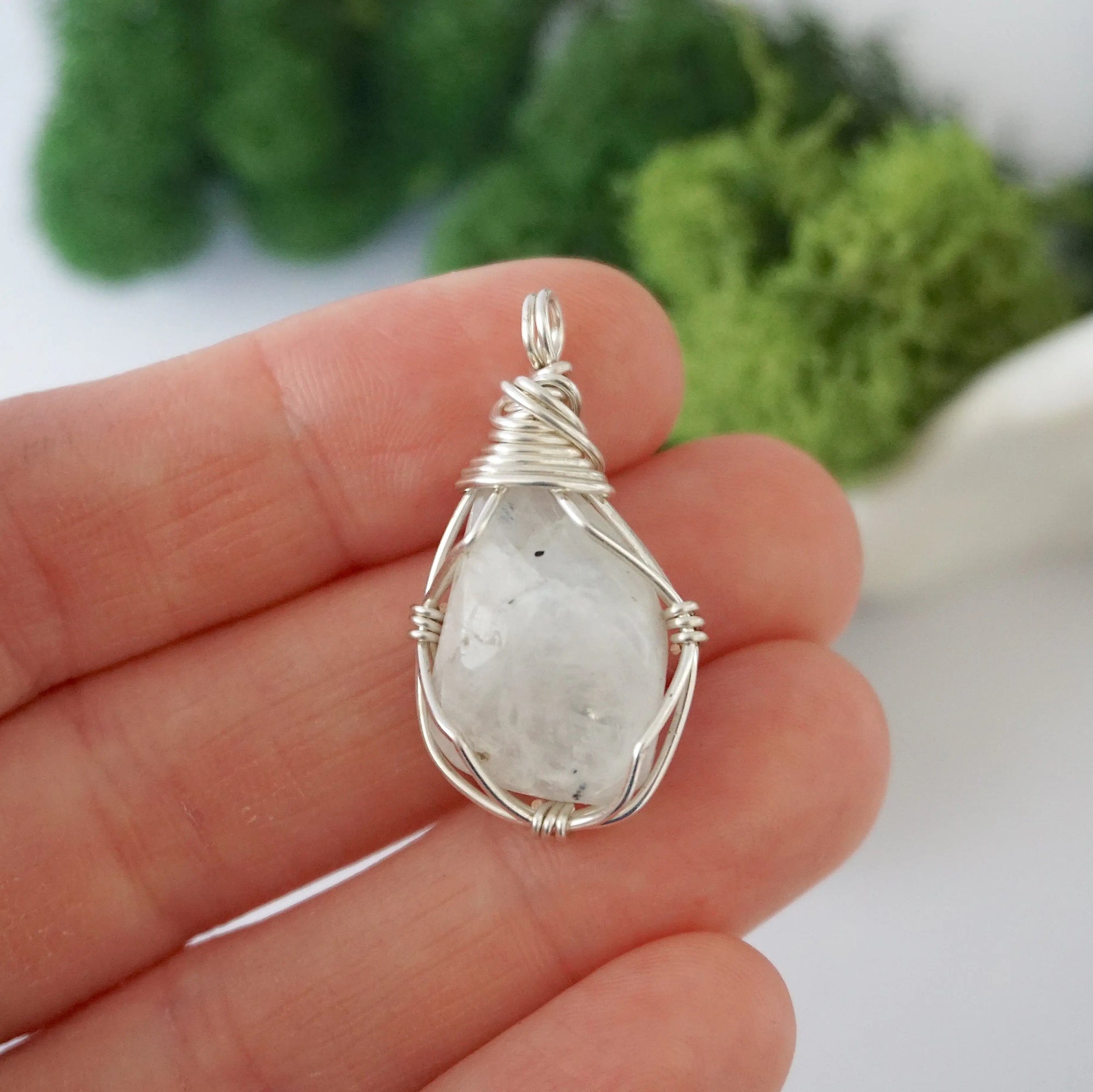 Simple raw rainbow moonstone pendant shown in hand for size reference