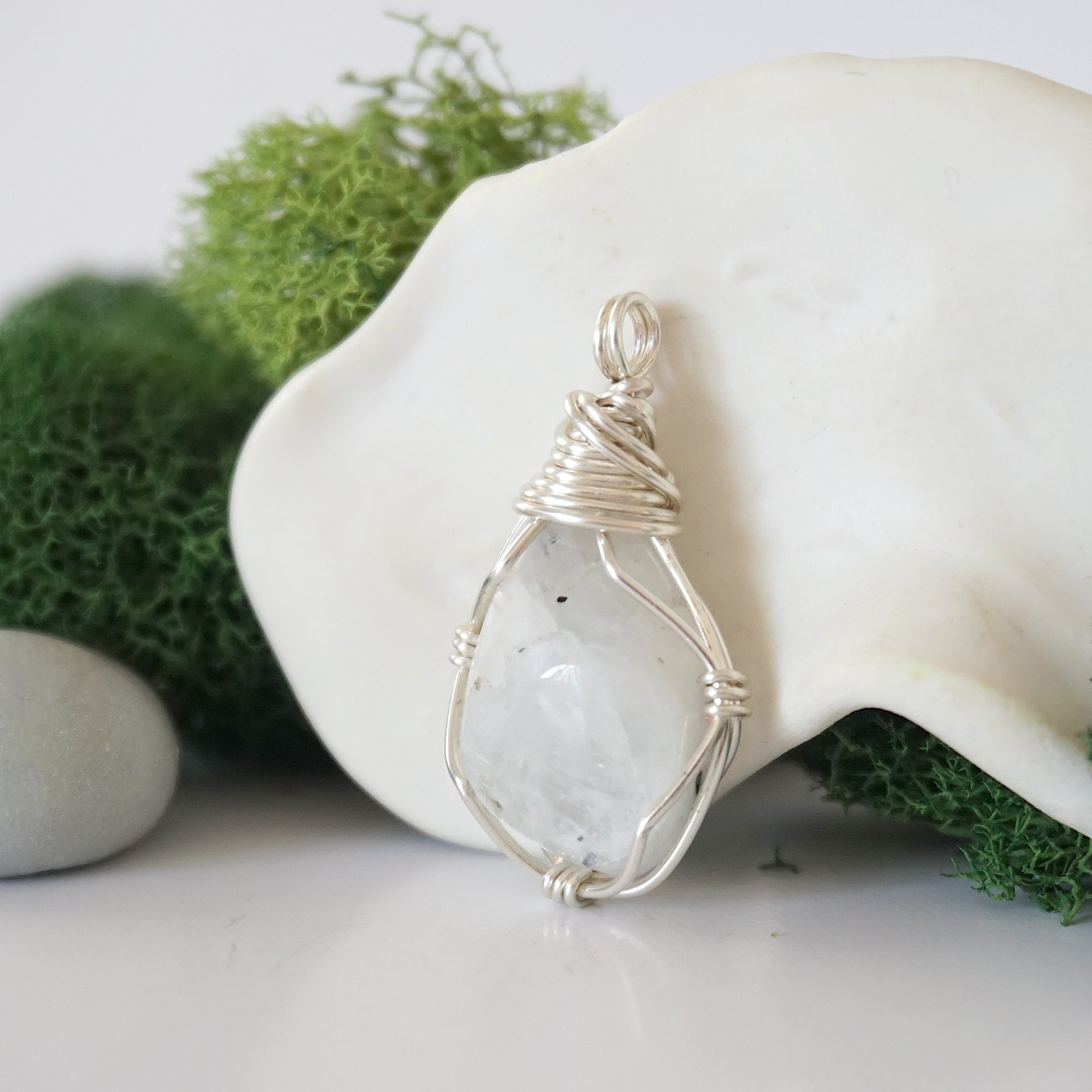 Detailed side angle view of simple raw rainbow moonstone pendant in silver wire