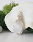 Detailed side angle view of simple raw rainbow moonstone pendant in silver wire