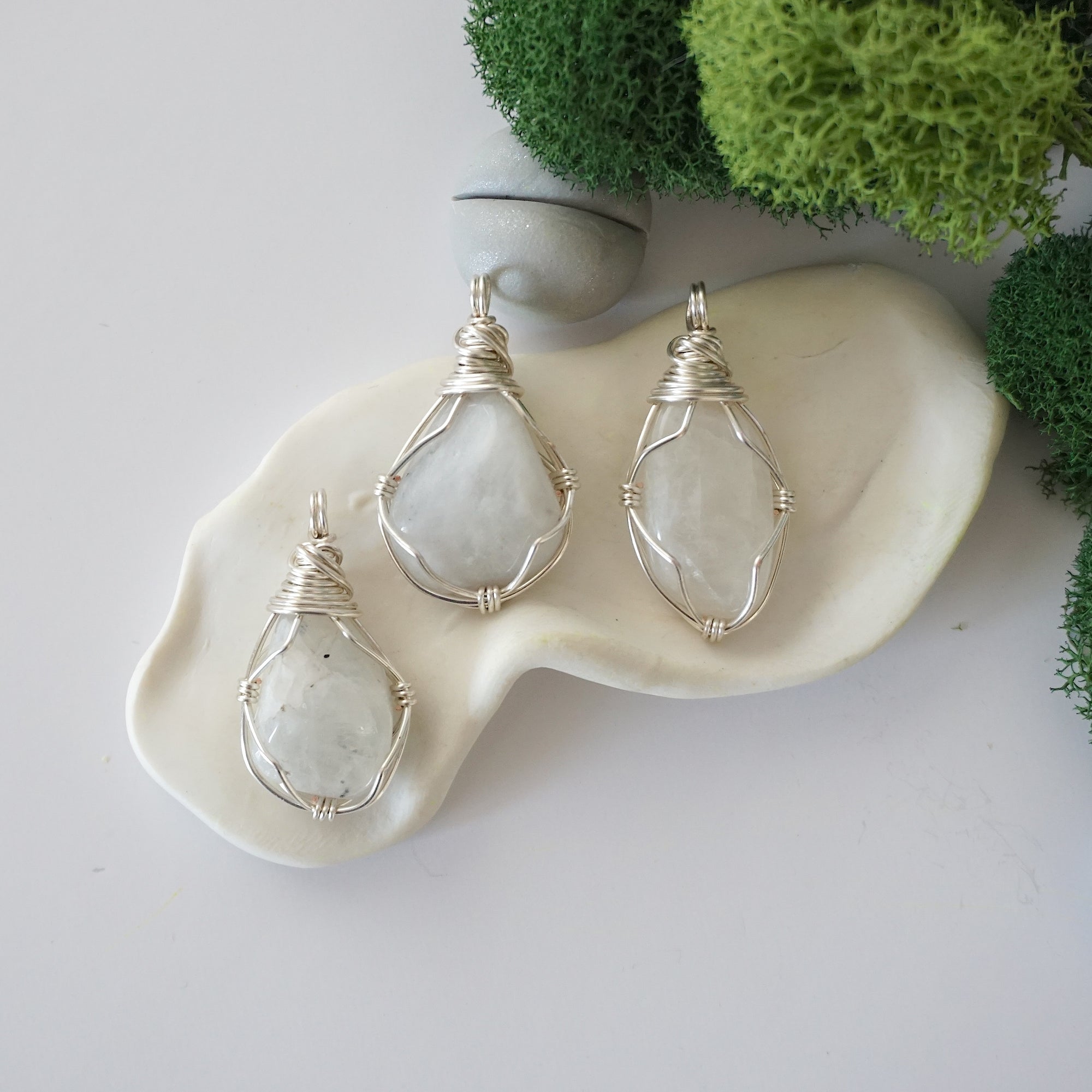 Three different raw rainbow moonstone pendants displayed for variation reference