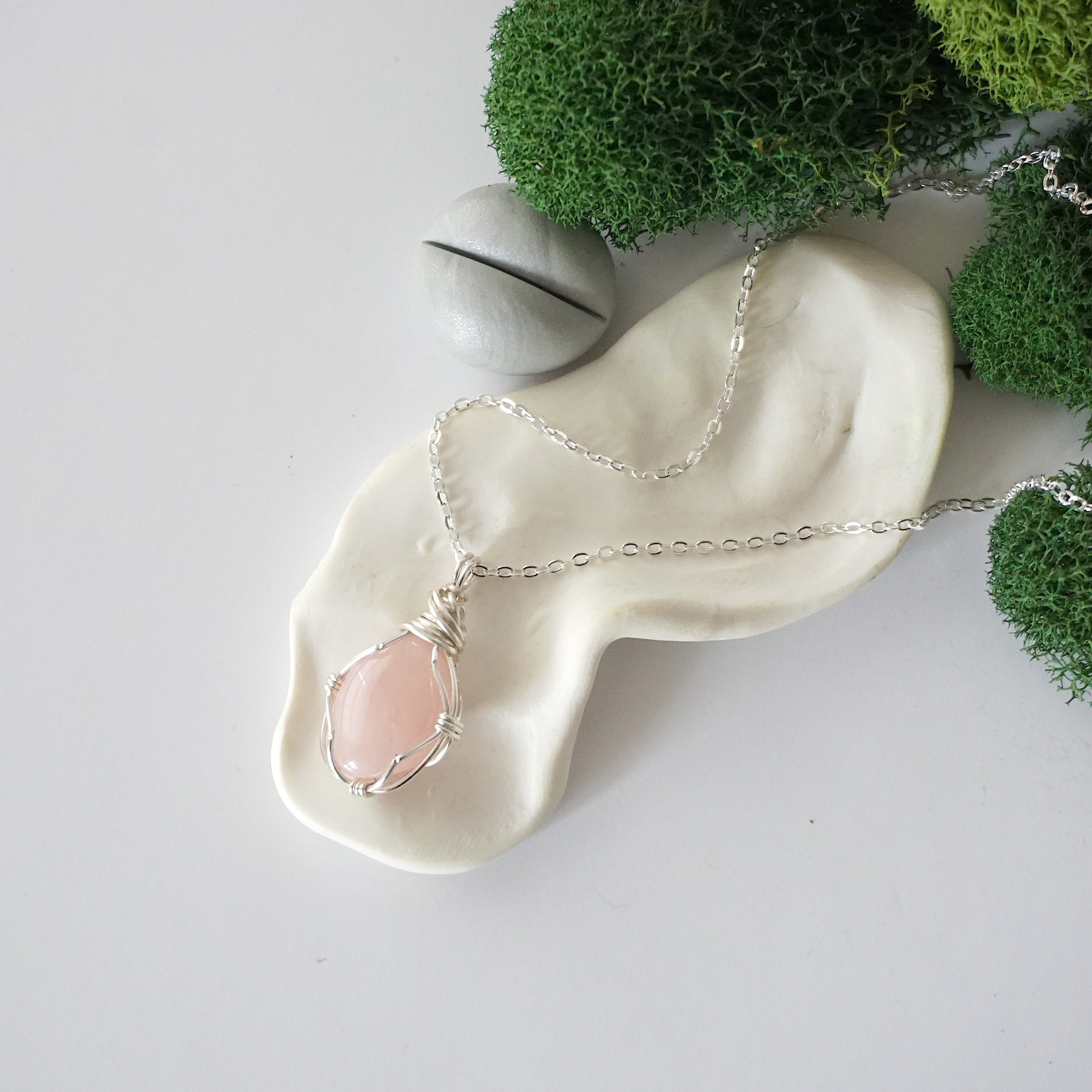 Simple raw rose quartz necklace with silver plated brass chain laying flat