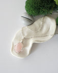 Simple raw rose quartz necklace with silver plated brass chain laying flat