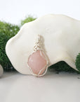 Back angle look at simple raw rose quartz pendant with silver wire wrapping