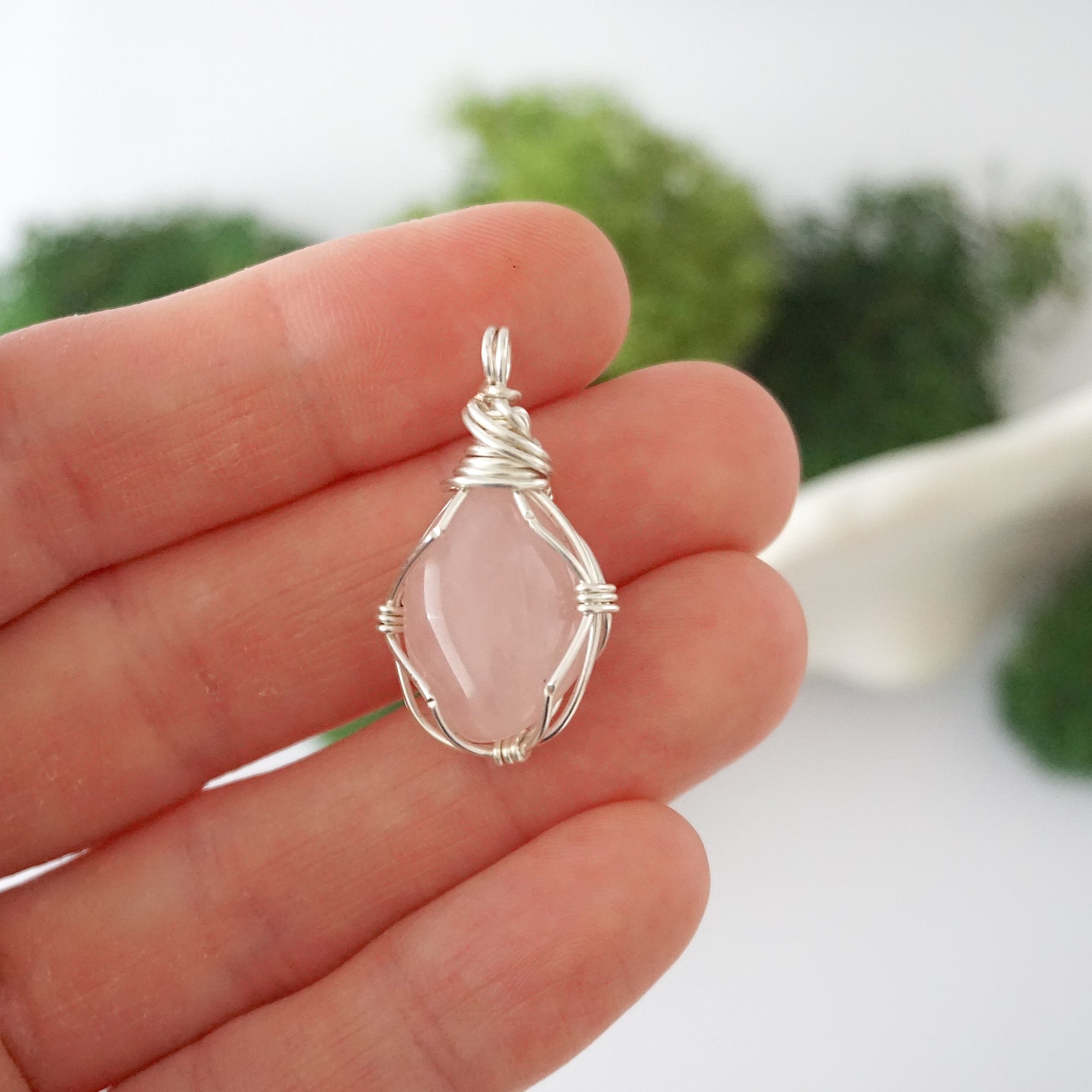 Simple raw rose quartz pendant shown in hand for size reference