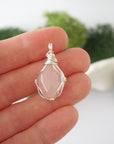 Simple raw rose quartz pendant shown in hand for size reference