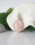 Detailed side angle view of simple raw rose quartz pendant in silver wire