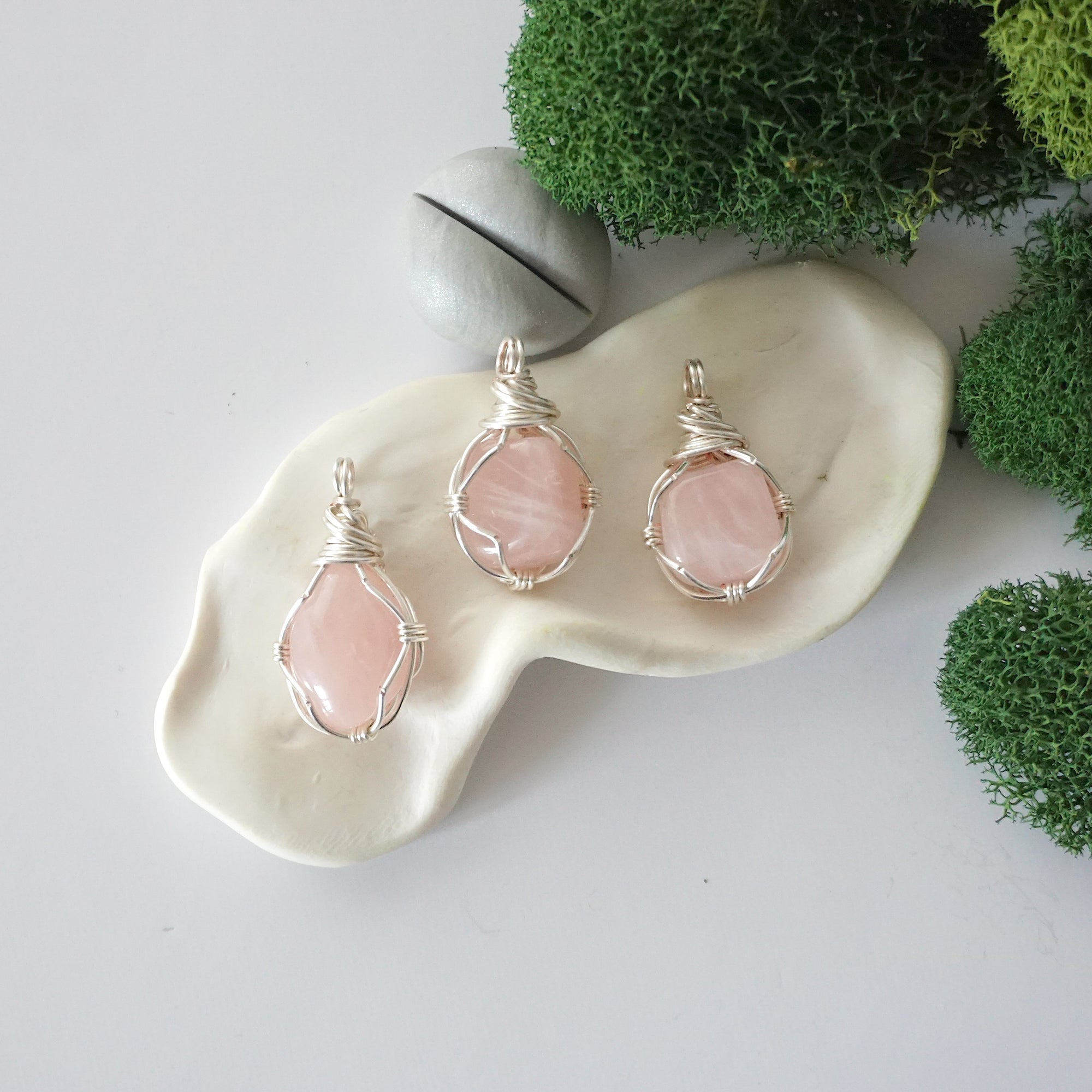 Three different raw rose quartz pendants displayed for variation reference