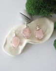 Three different raw rose quartz pendants displayed for variation reference
