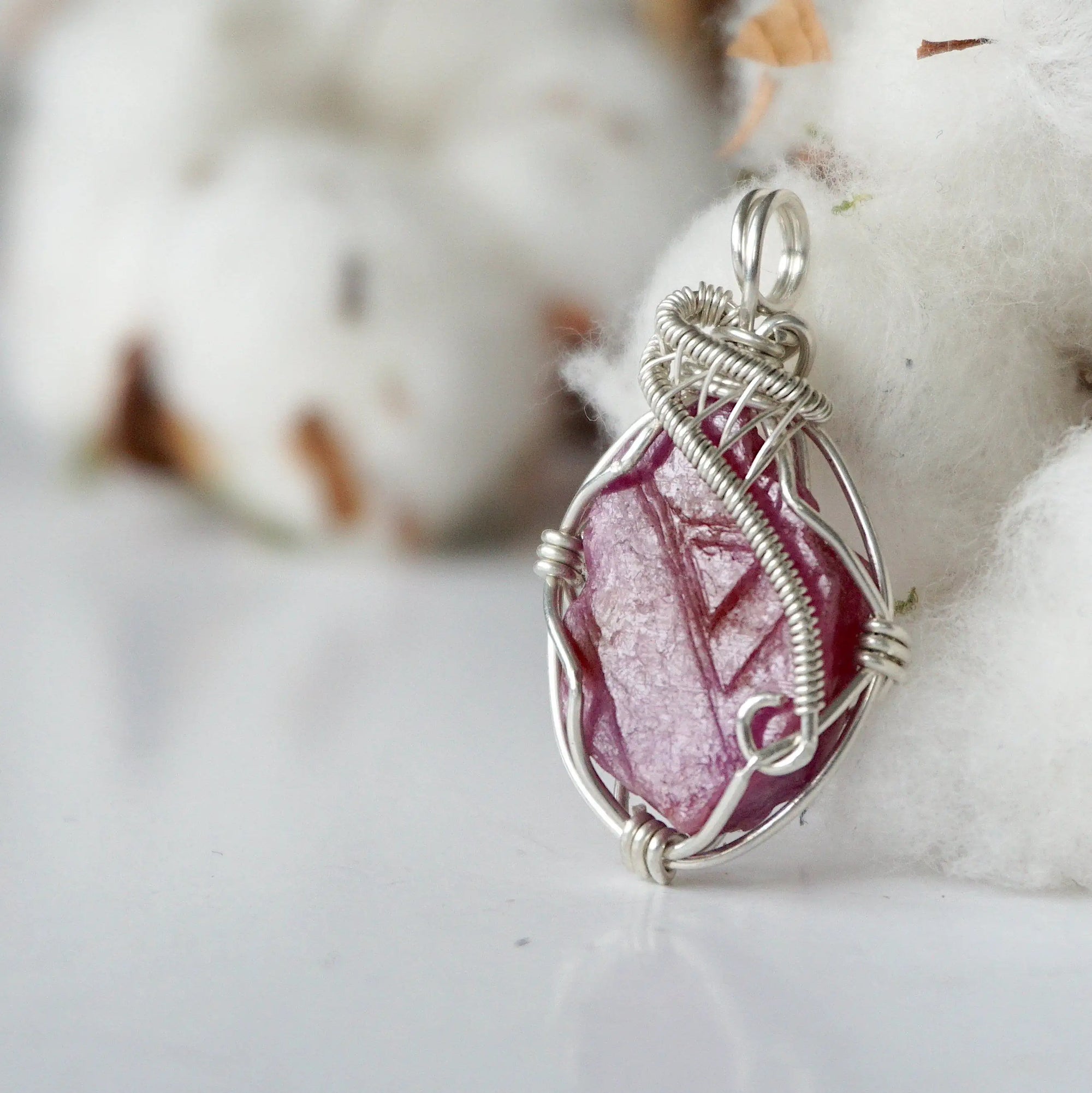 Side angle of raw ruby pendant, sterling silver artisan wire wrapping, showing detail and craftsmanship