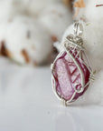 Side angle of raw ruby pendant, sterling silver artisan wire wrapping, showing detail and craftsmanship