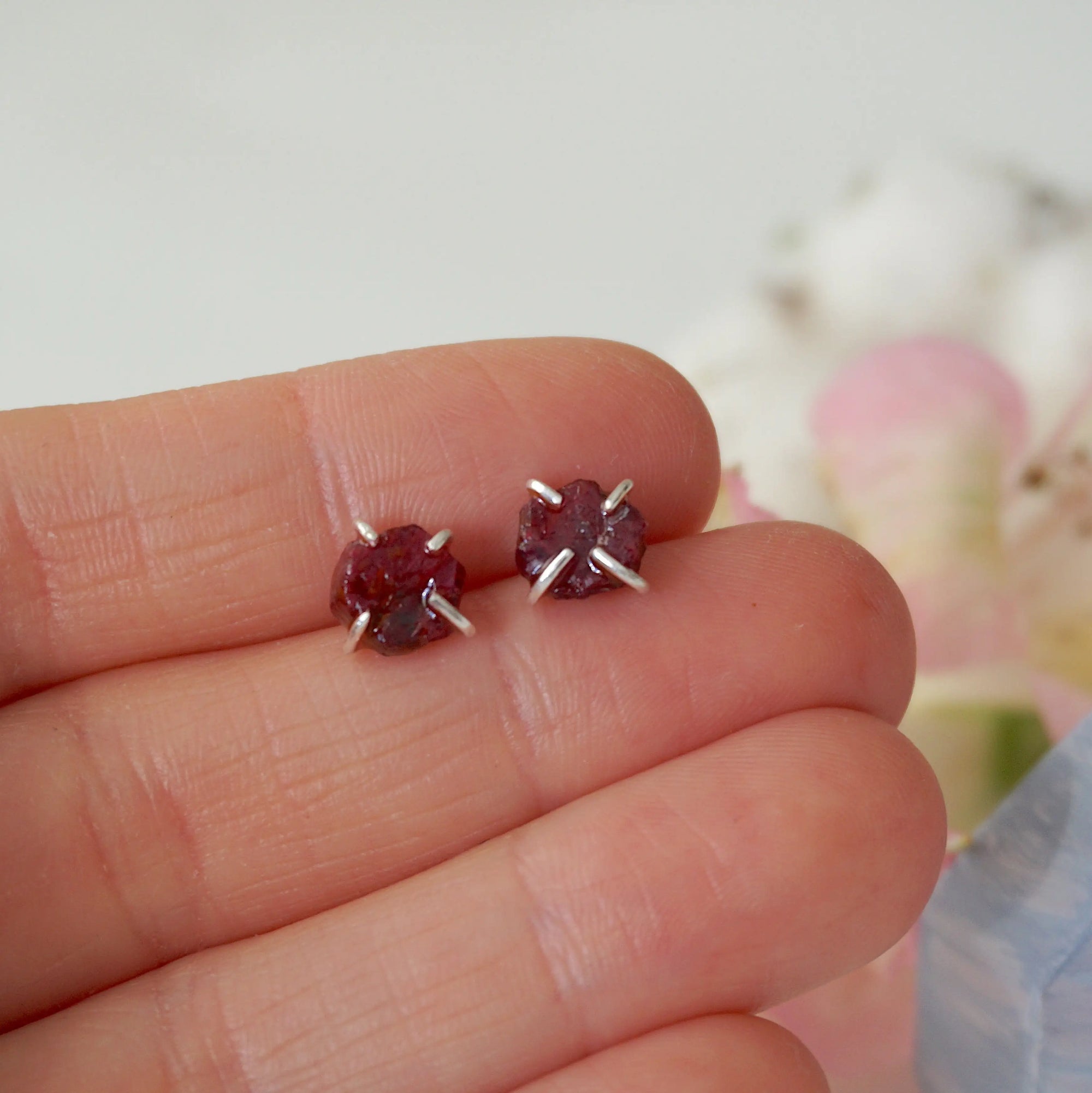 Raw ruby prong stud earrings held in hand to show size — genuine raw ruby in 925 sterling silver setting, July birthstone earrings