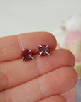 Raw ruby prong stud earrings held in hand to show size — genuine raw ruby in 925 sterling silver setting, July birthstone earrings