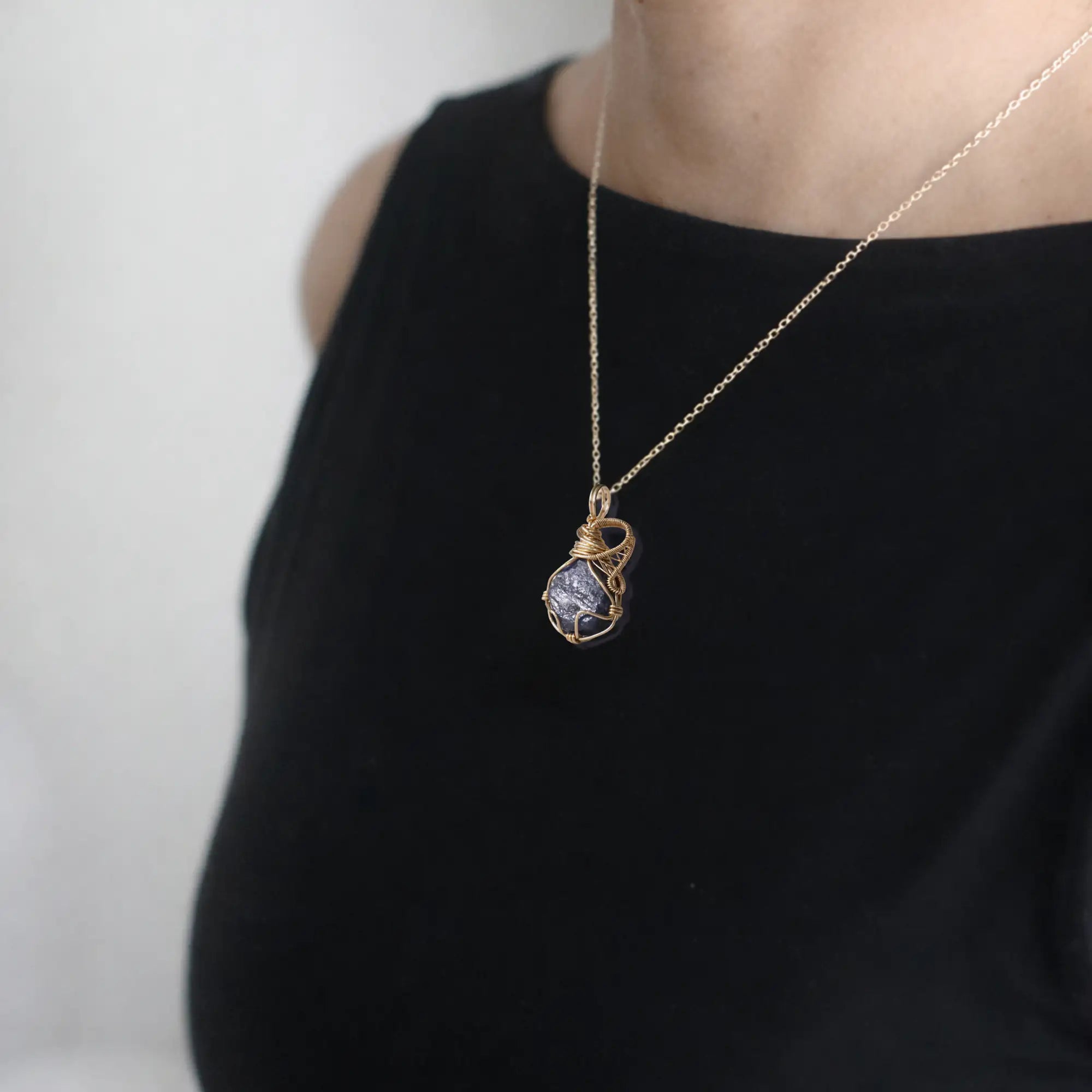 Raw sapphire necklace in 14k gold filled on a female model. Handcrafted September birthstone jewelry for women by Designs by Nature Gems.