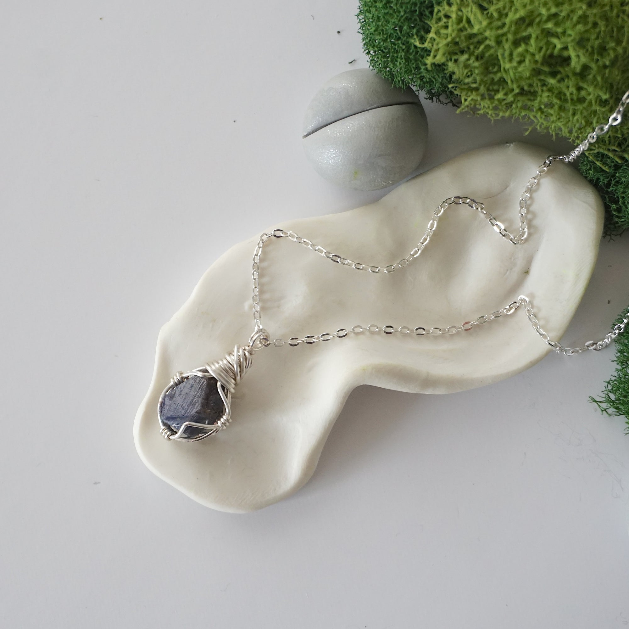 Simple raw sapphire necklace with silver plated brass chain laying flat