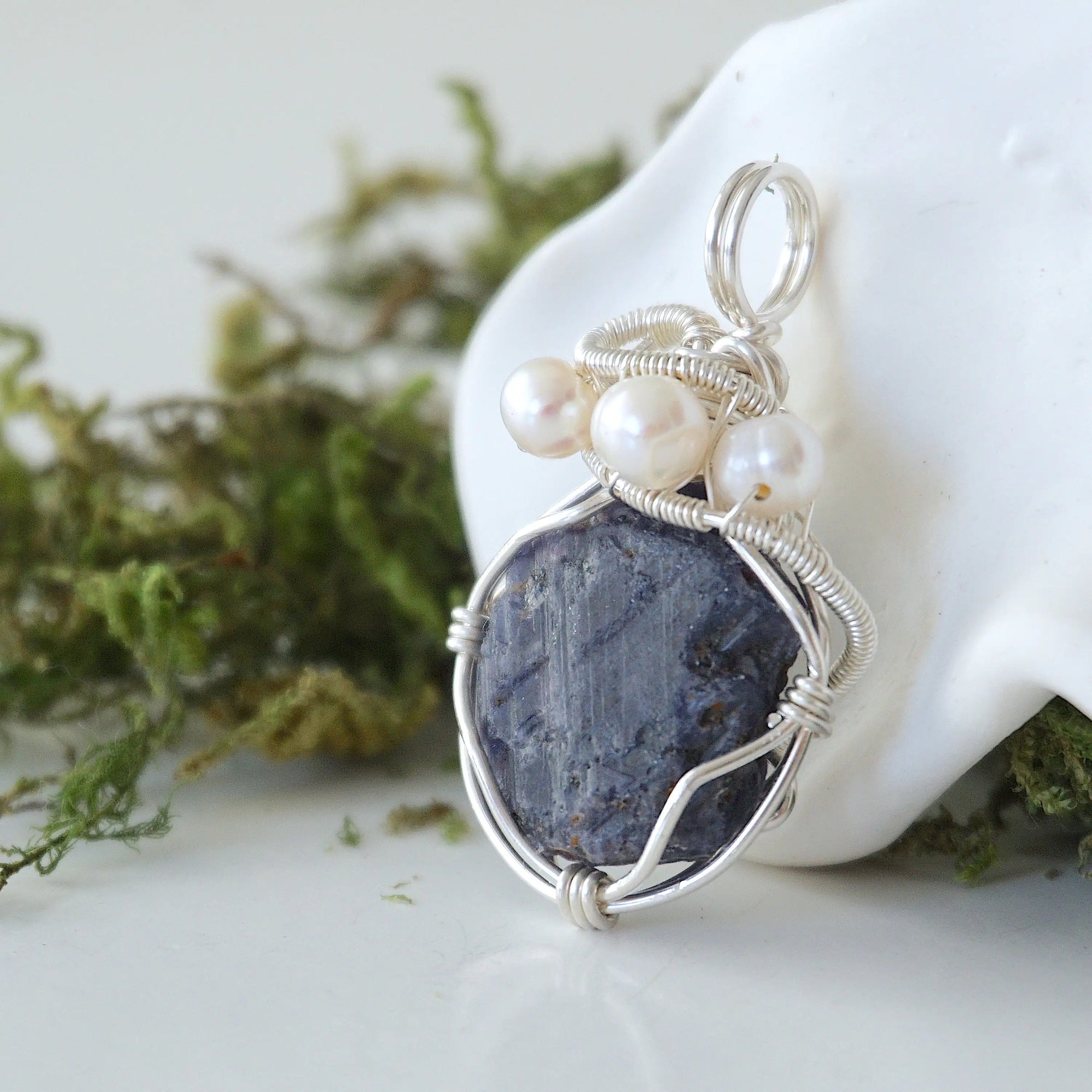 Left-angle close-up of raw sapphire and freshwater pearl pendant revealing the precision of 925 sterling silver wire-wrapping craftsmanship
