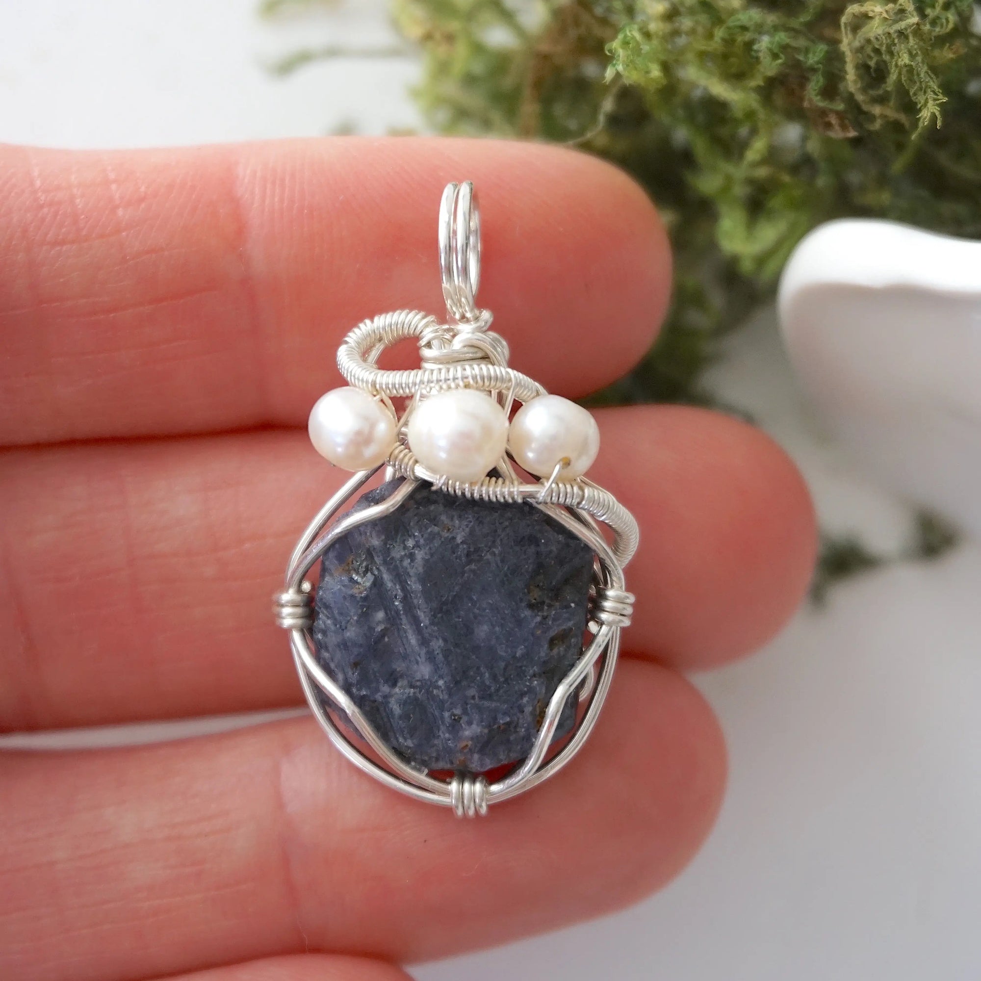 Raw sapphire and freshwater pearl pendant held in hand to show size — 925 sterling silver wire wrap, handcrafted crystal jewelry by Designs by Nature Gems
