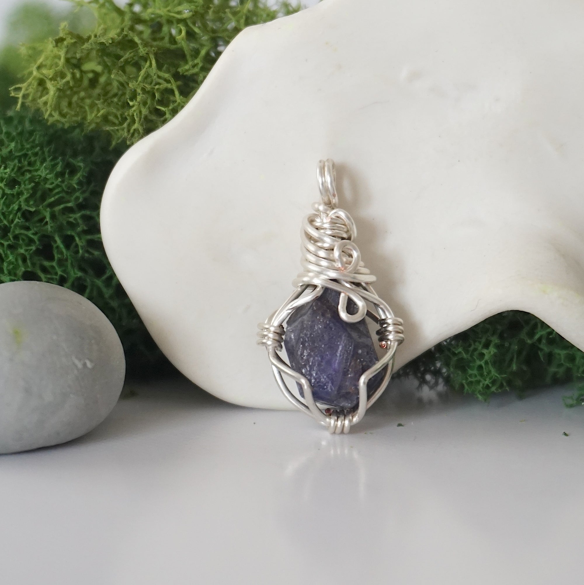 Back angle look at simple raw sapphire pendant with silver wire wrapping