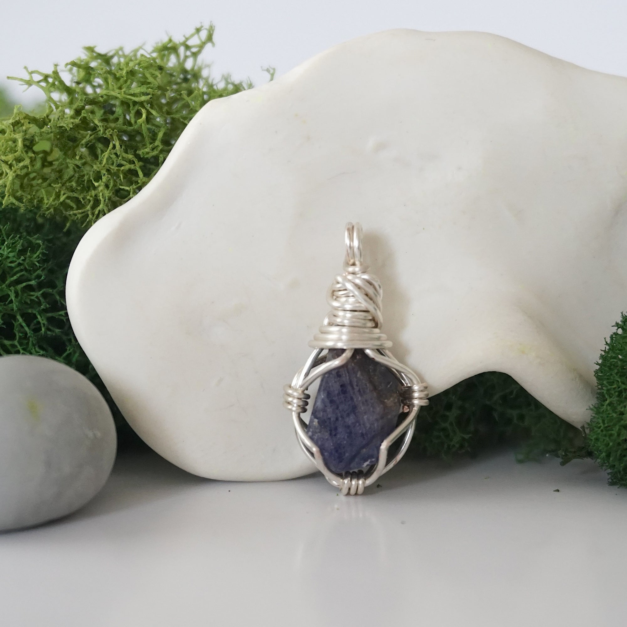 Detailed front angle view of simple raw sapphire pendant in silver wire