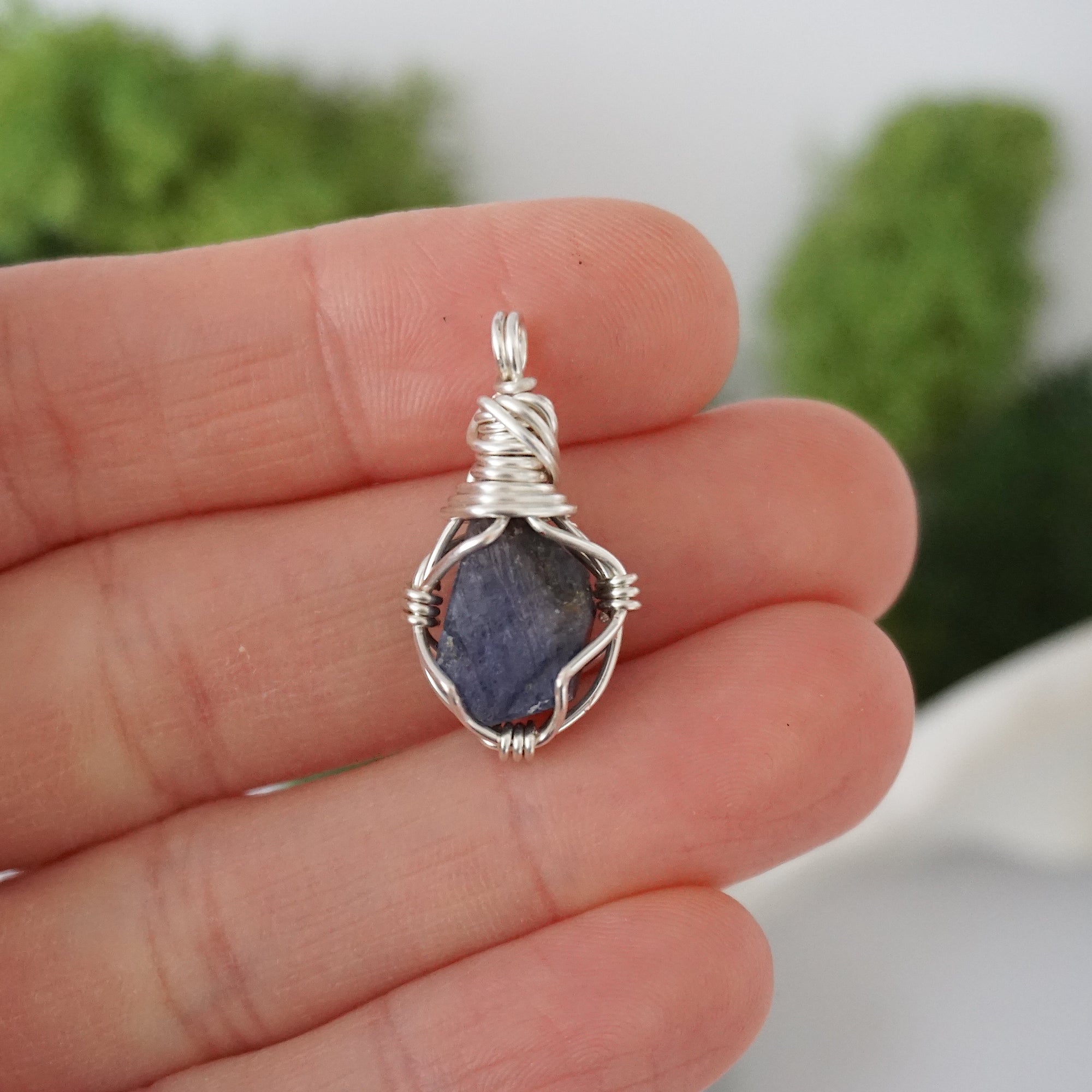 Simple raw sapphire pendant shown in hand for size reference