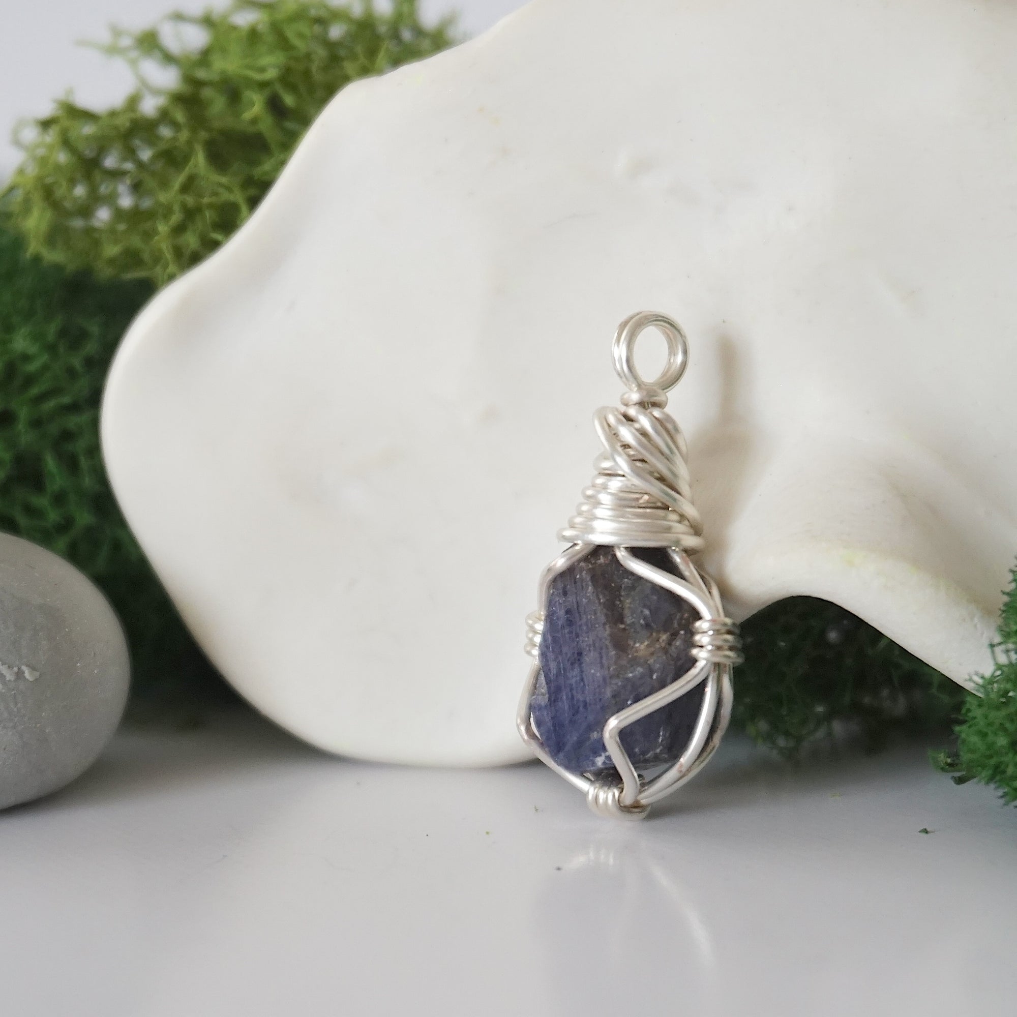Detailed side angle view of simple raw sapphire pendant in silver wire