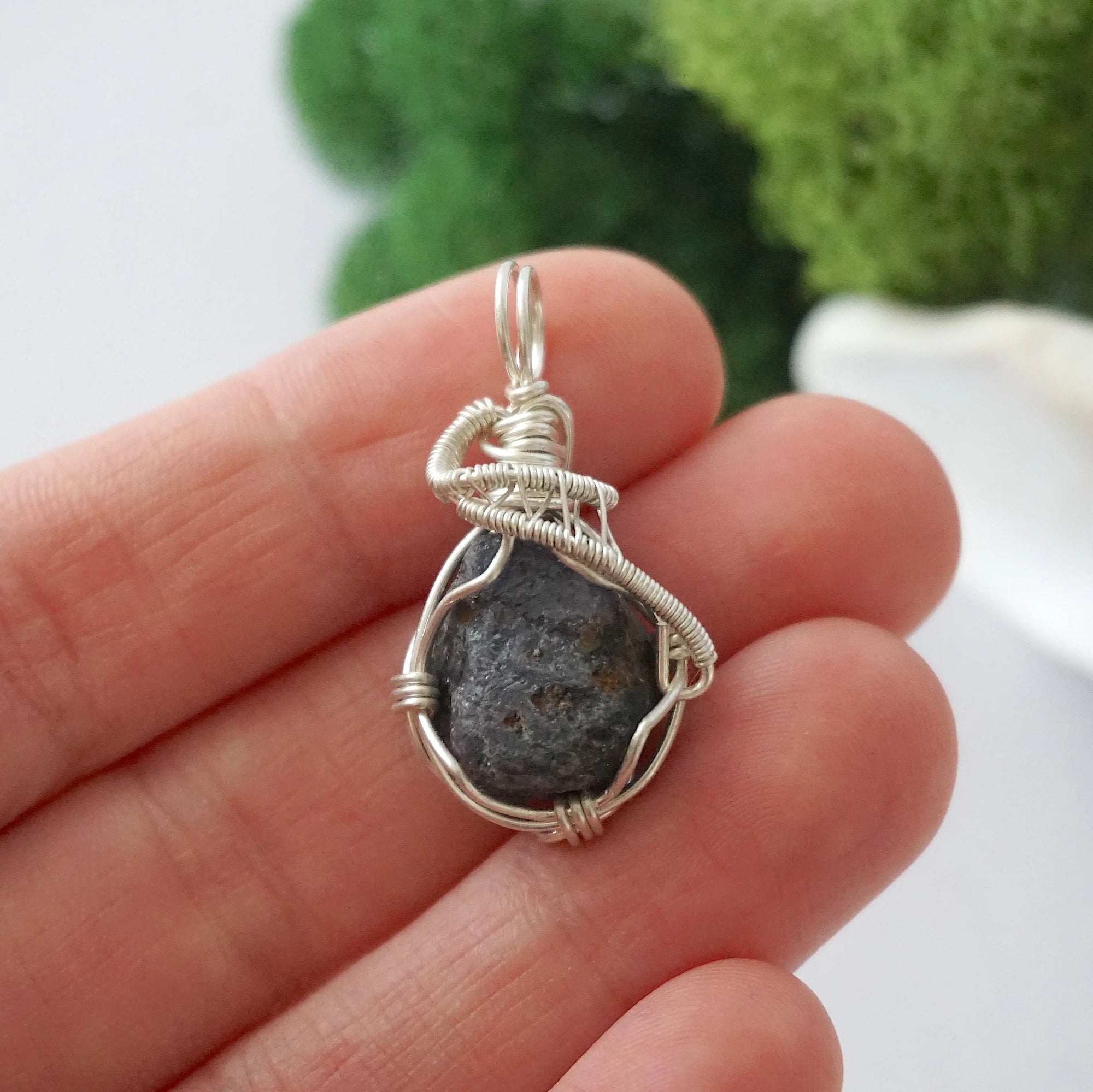 Handmade raw sapphire pendant held in hand showing size — natural dark blue sapphire stone wire wrapped in 925 sterling silver, 25-30 carats, one of a kind