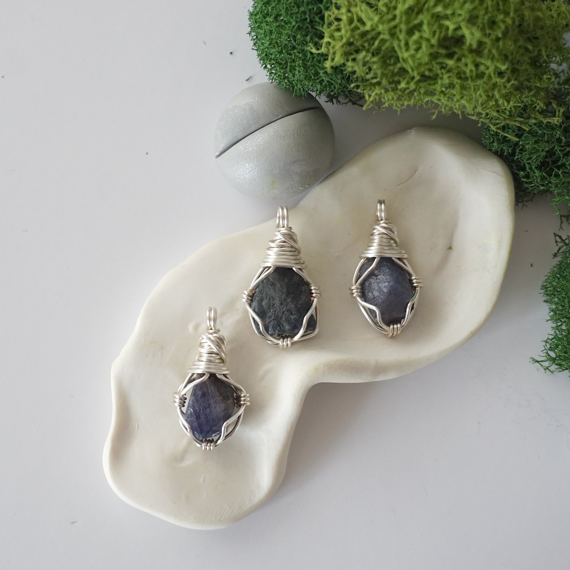 Three different raw sapphire pendants displayed for variation reference