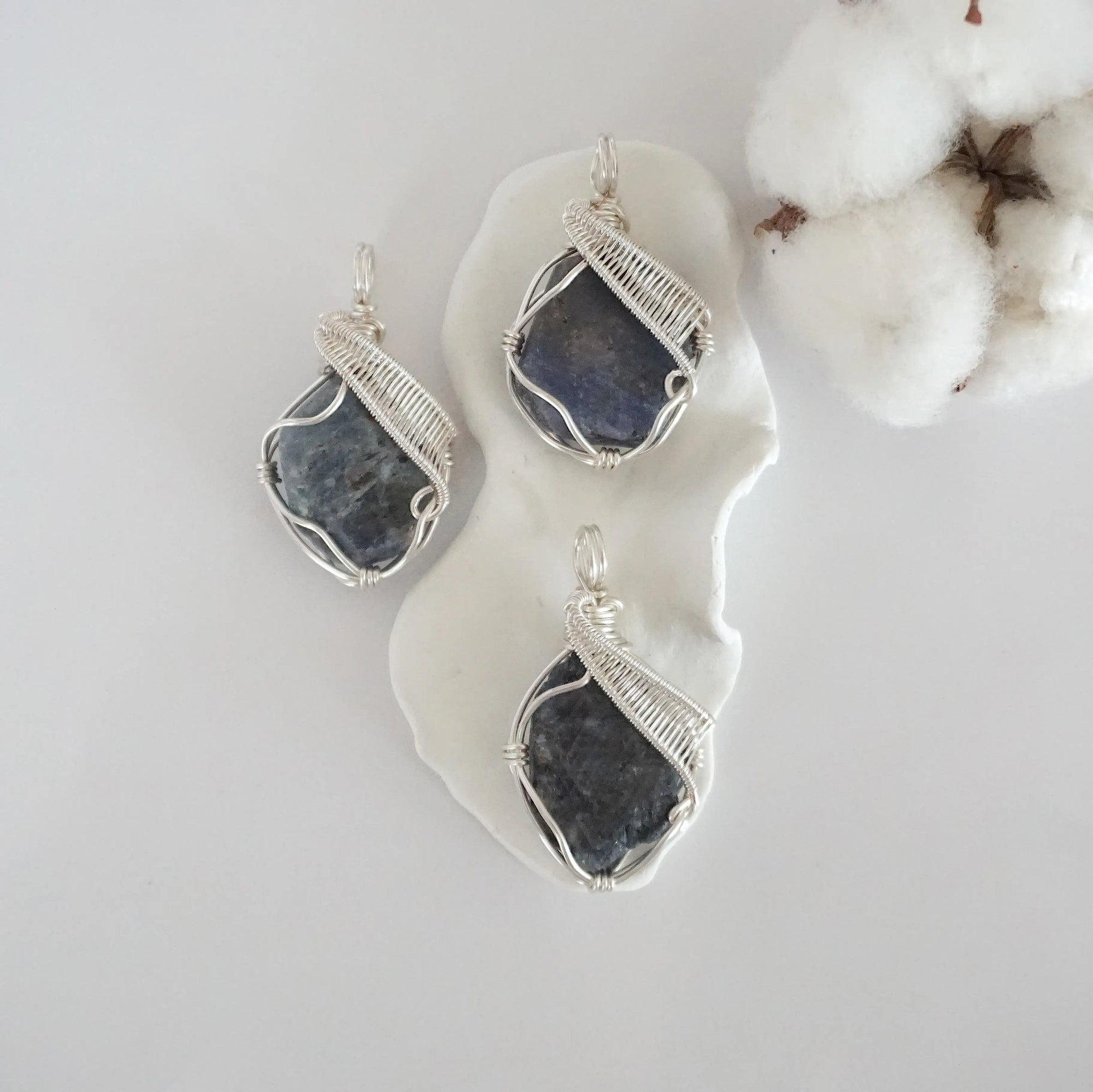 Three raw sapphire pendants showing natural variation in stone size, shape, and blue-grey tone — each one of a kind, September birthstone, silver wire wrapped, Designs by Nature Gems