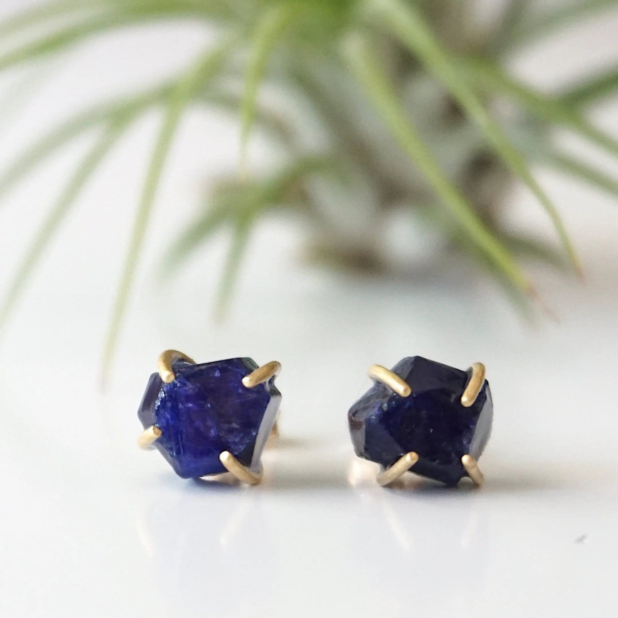 Front view of genuine raw sapphire stud earrings showing their natural blue colour and minimalist 14k gold vermeil prong settings