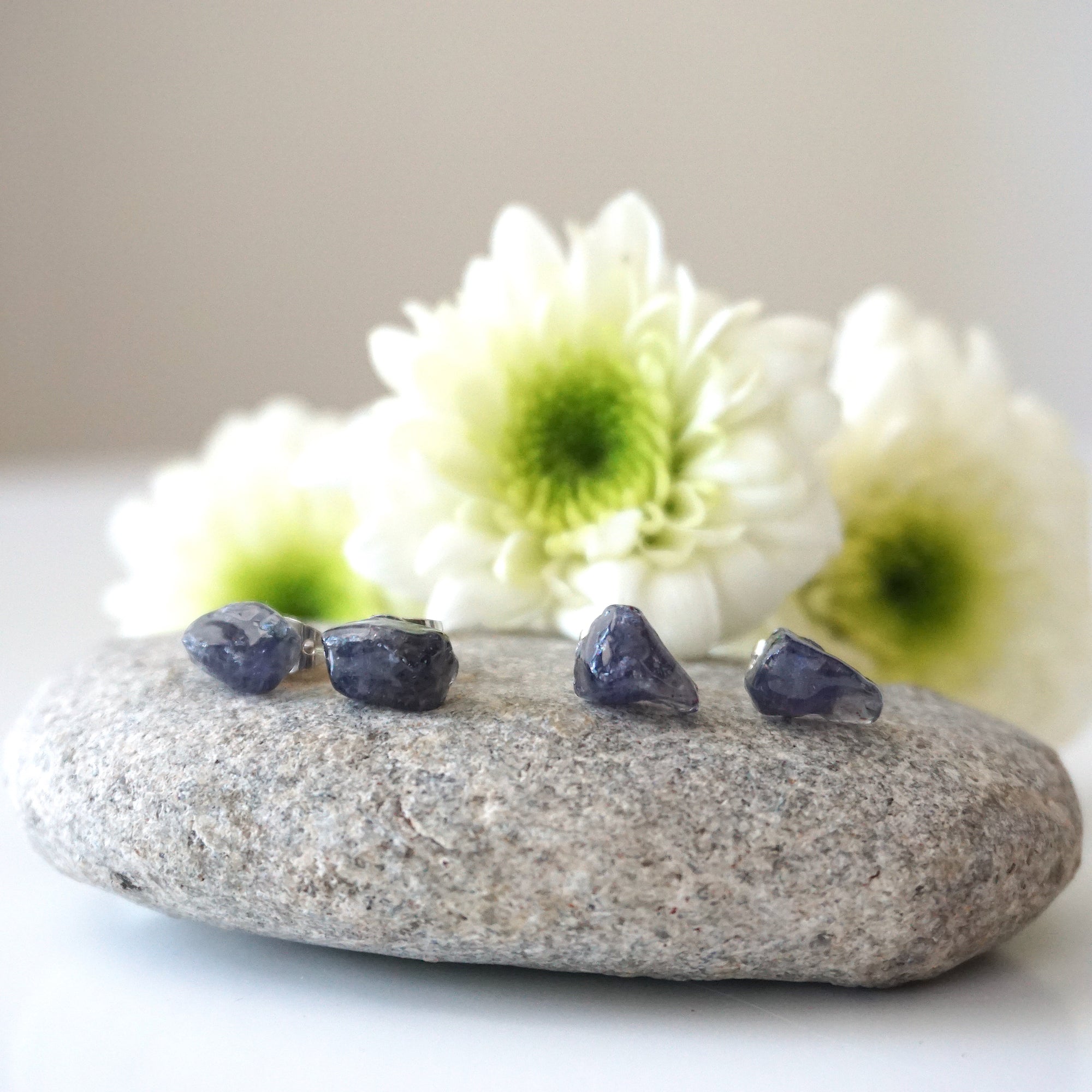 Two pairs of raw sapphire stud earrings showing natural variation in stone shape, size, and shade of blue — each pair is one of a kind