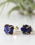 Slight-angle view of genuine raw sapphire stud earrings in 14k gold vermeil prong settings — minimalist September birthstone jewelry