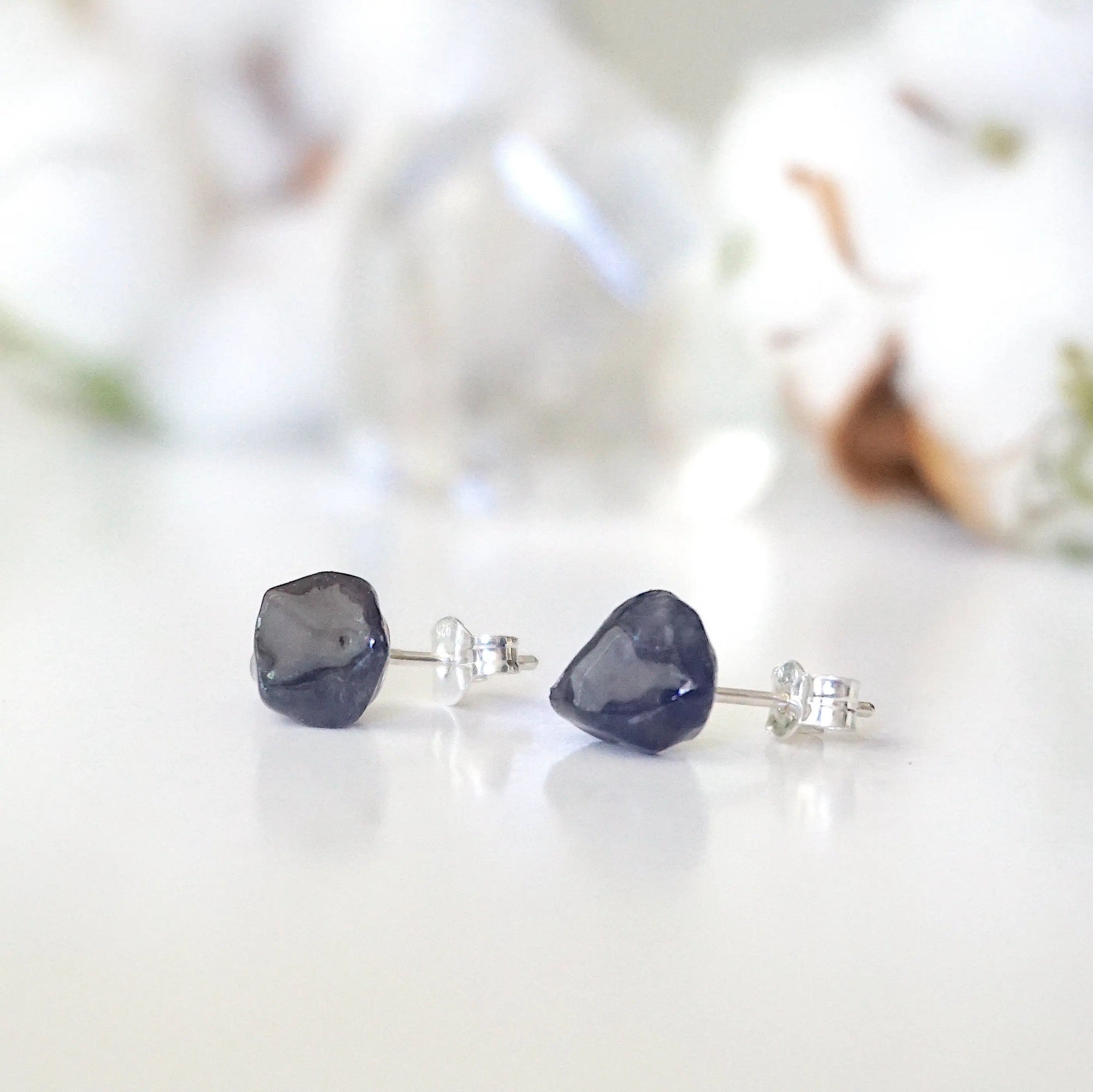 Slight-angle view of natural raw sapphire stud earrings on 925 sterling silver posts — minimalist September birthstone jewelry by Designs by Nature Gems